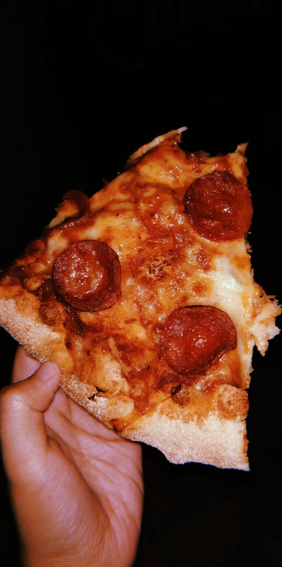 A person holding up some pizza with pepperoni - Pizza