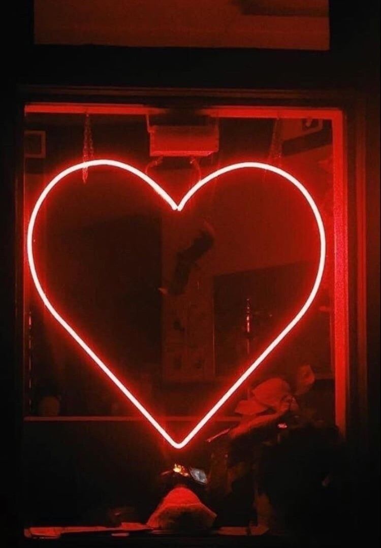 A heart shaped neon sign in the window of an establishment - Black heart, heart