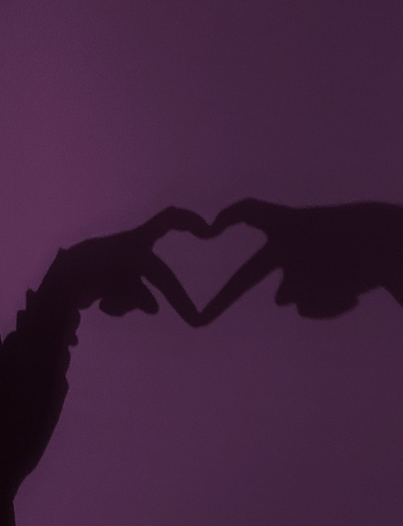 A pair of hands making a heart shape against a purple background - Black heart