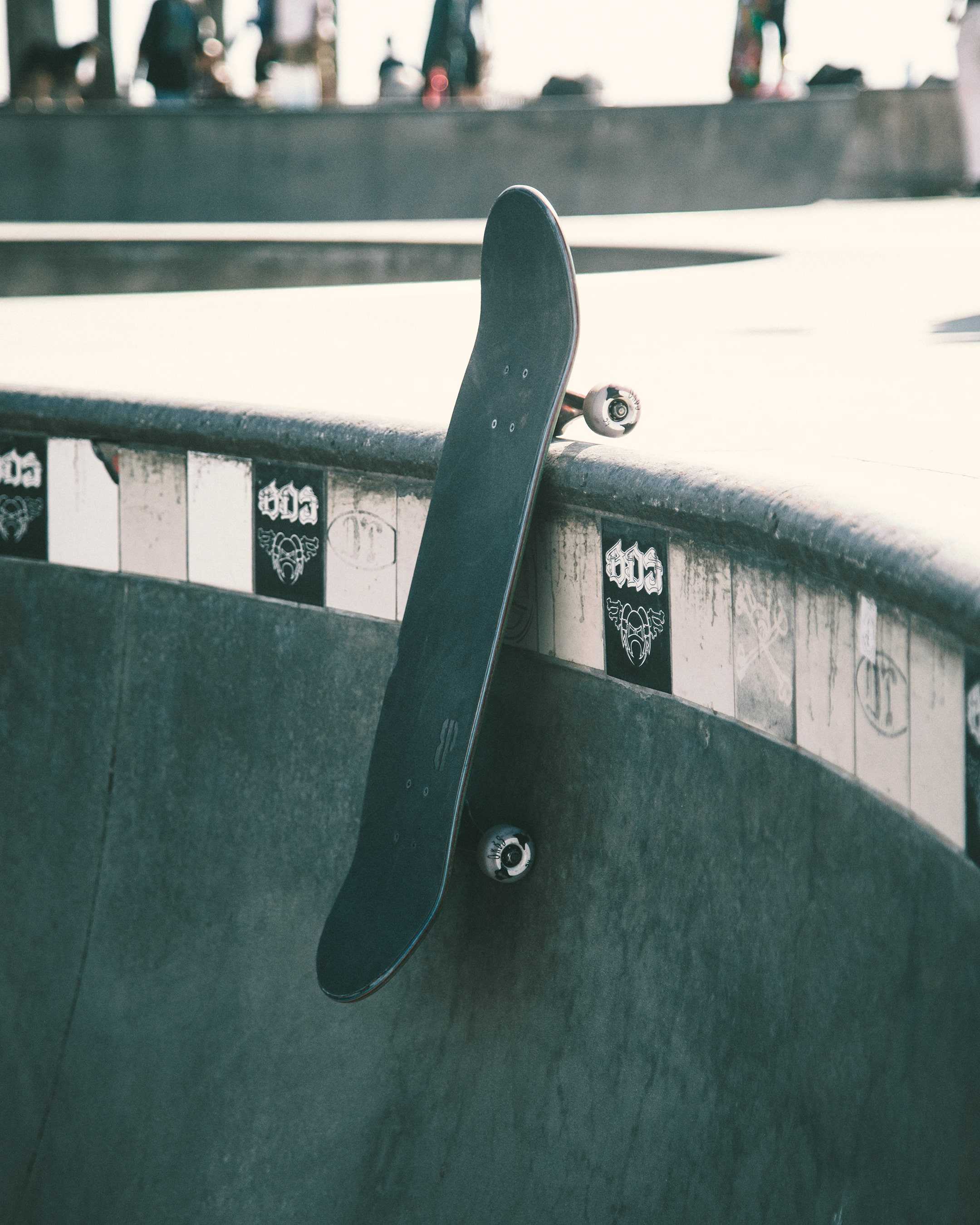 A skateboard is stuck in the side of a ramp at a skate park. - Skate