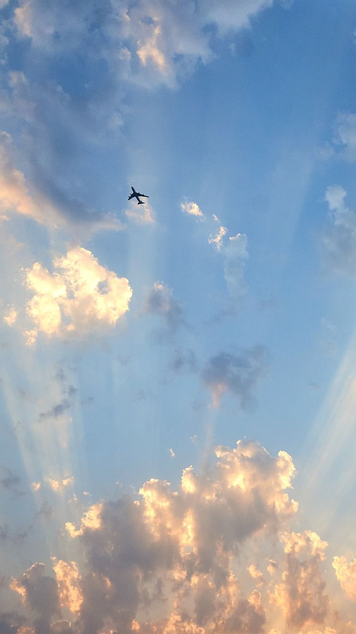 A plane flying through the clouds during a beautiful sunset. - Vintage clouds