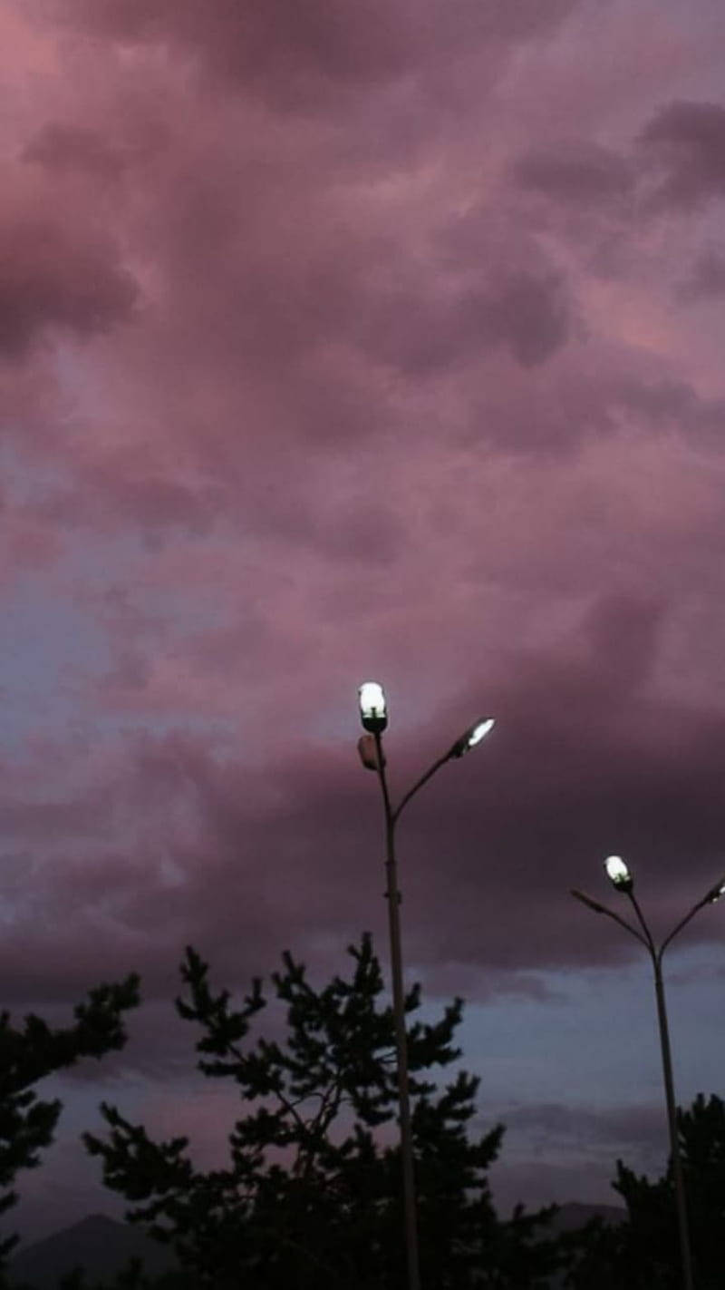 Street lights on a pole with a pink and purple sky in the background - Vintage clouds