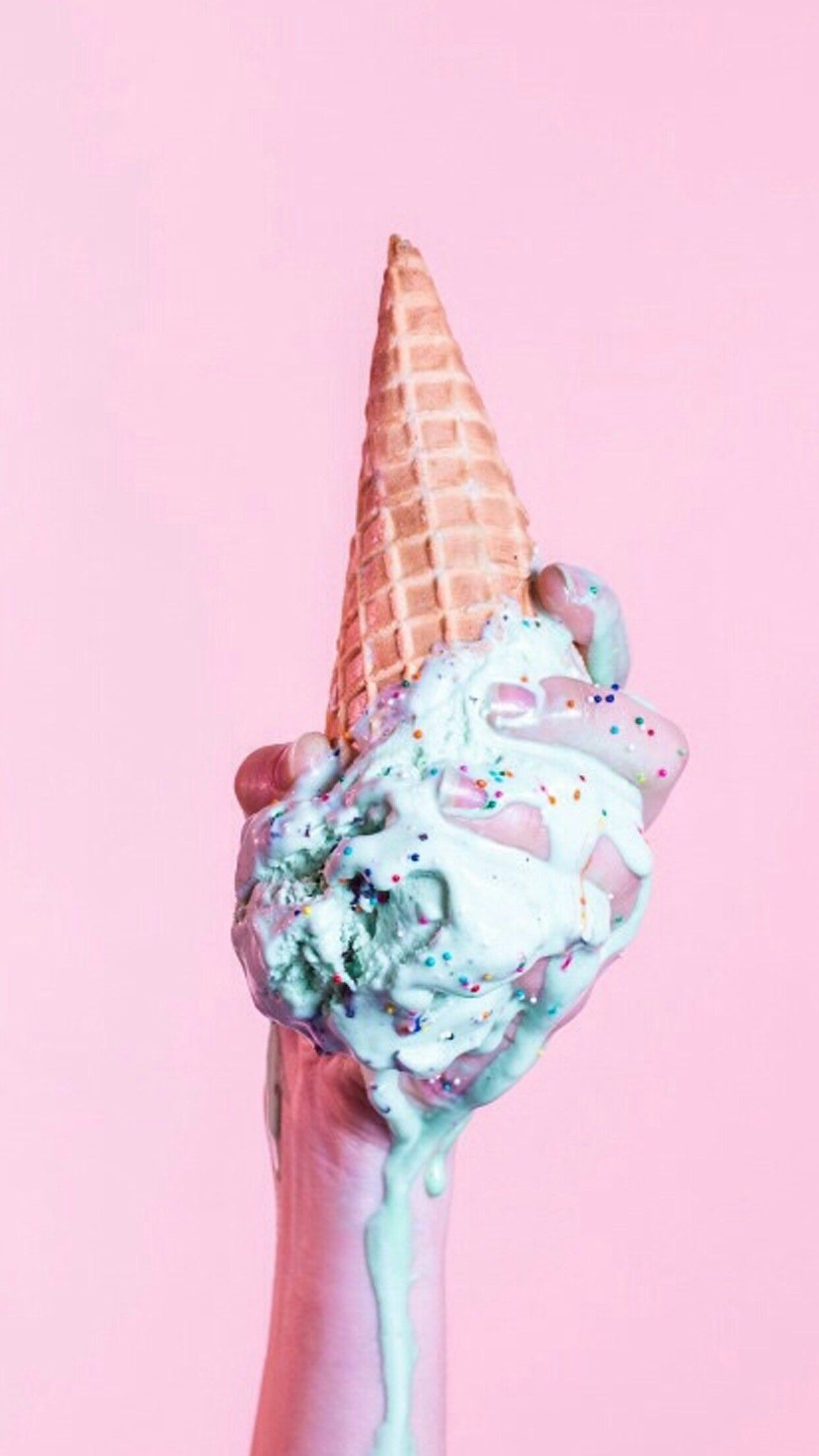 A person holding an ice cream cone with green and pink paint on it - Ice cream