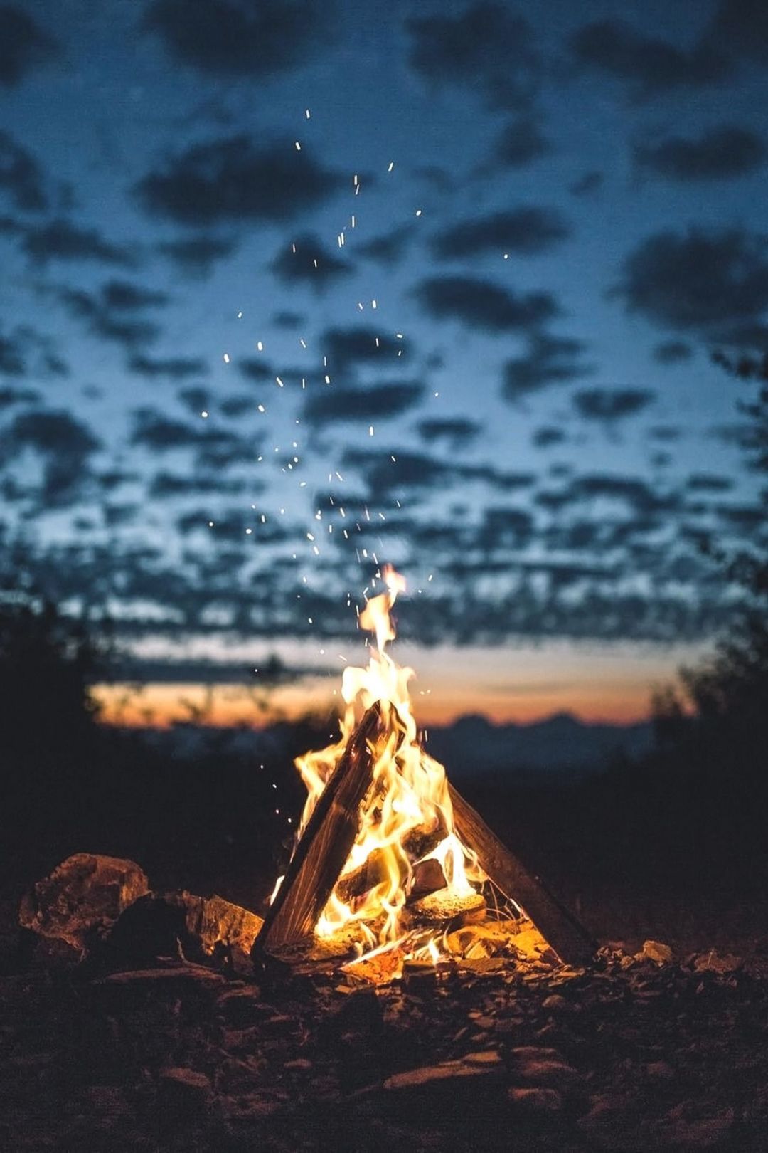 A campfire burns in the dark of night, surrounded by rocks. - Fire
