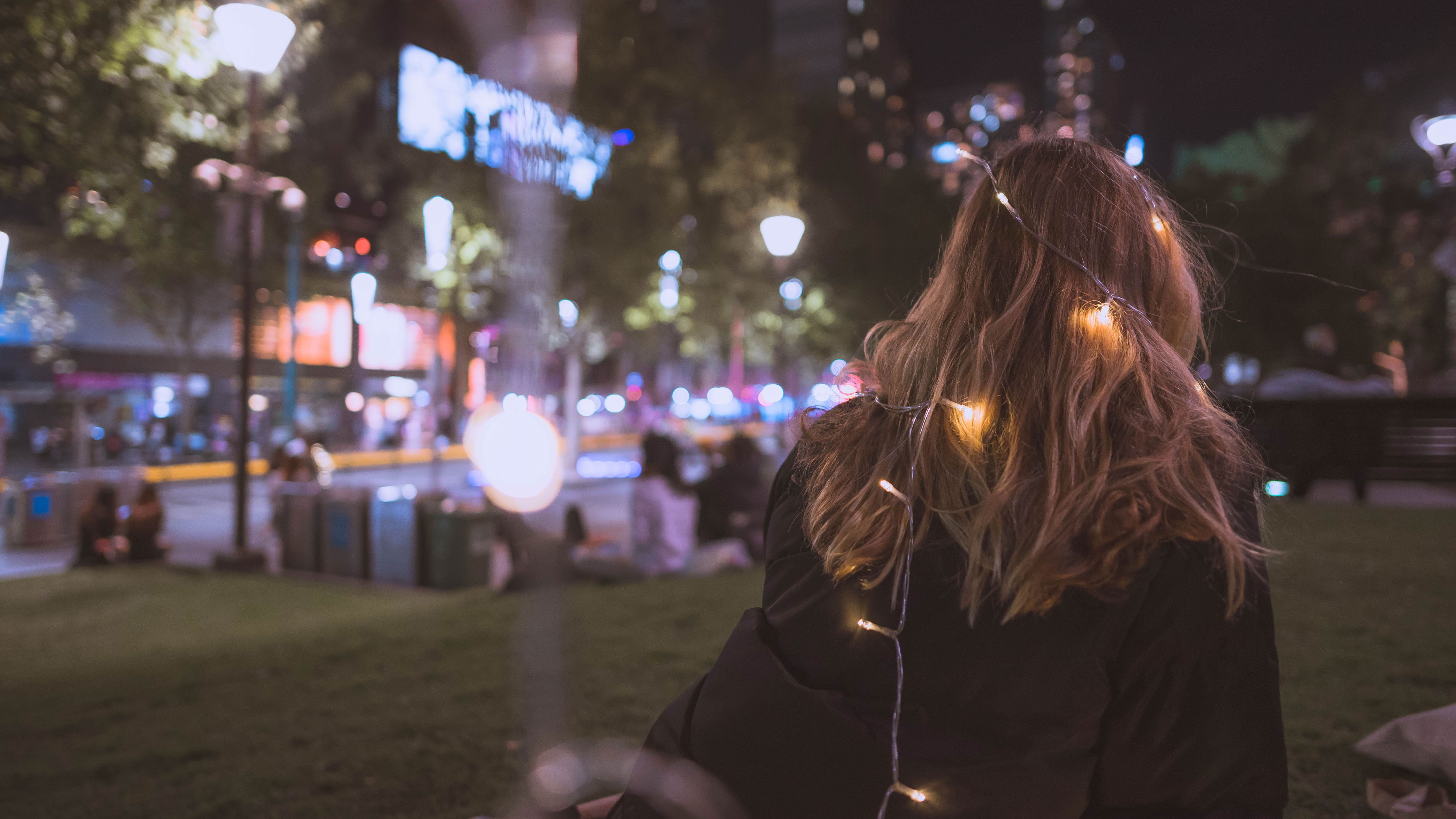 A woman sitting on the ground in front of some lights - Grunge