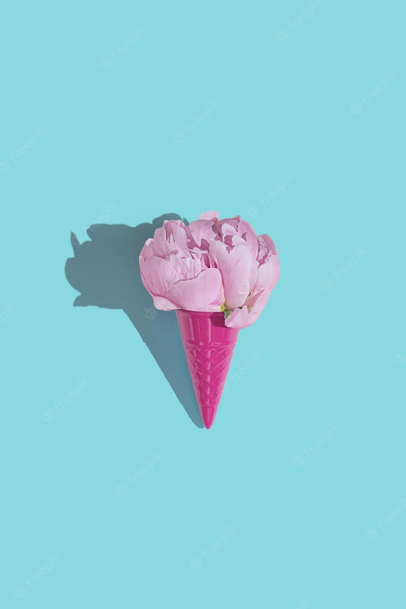 Premium Photo. Creative pink toy ice cream cone with pink peony fluffy flower on blue minimal background with copy space flat lay botany idea for summer or spring wallpaper or greeting