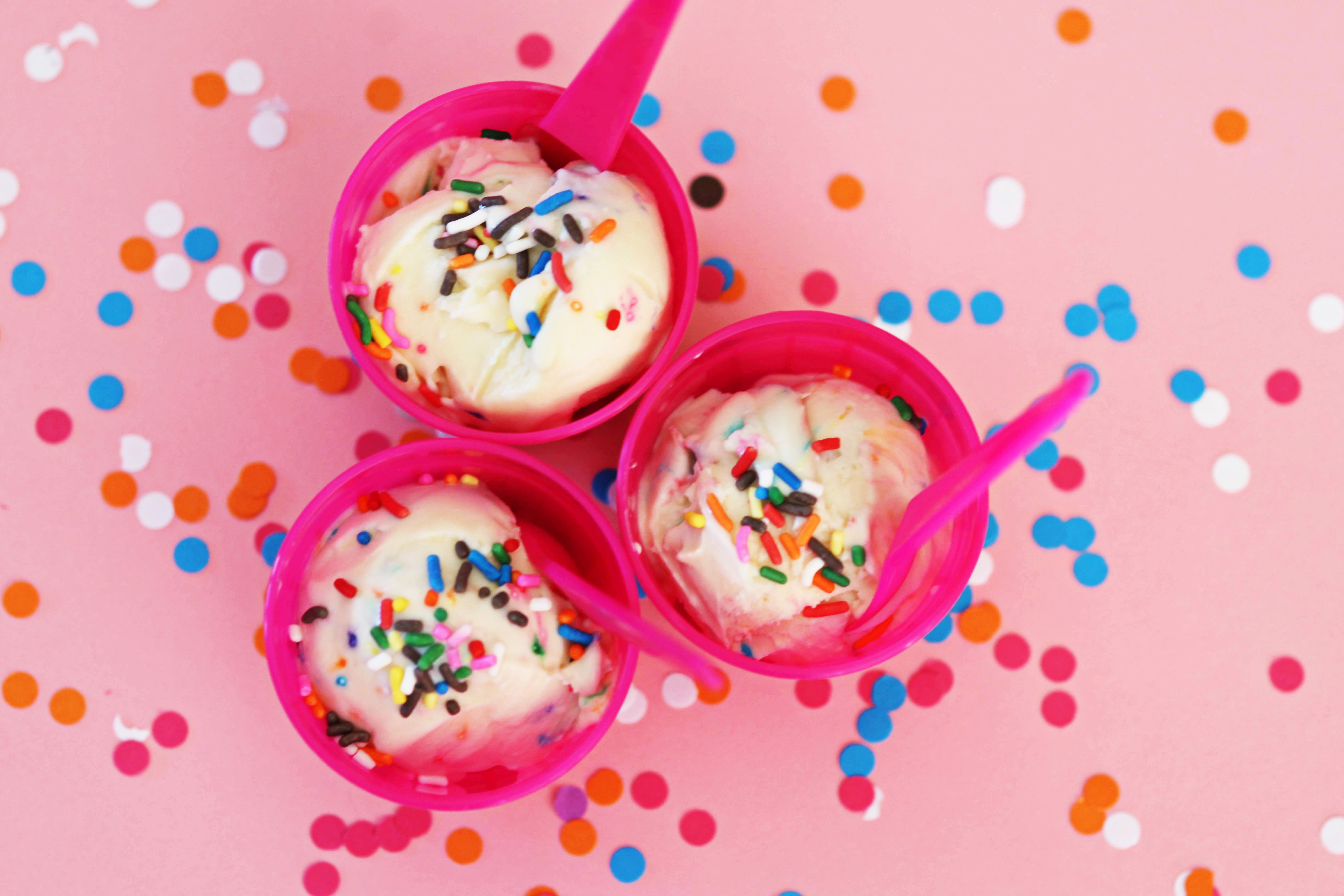 Pink bowls of vanilla ice cream with sprinkles on a pink background with confetti. - Ice cream