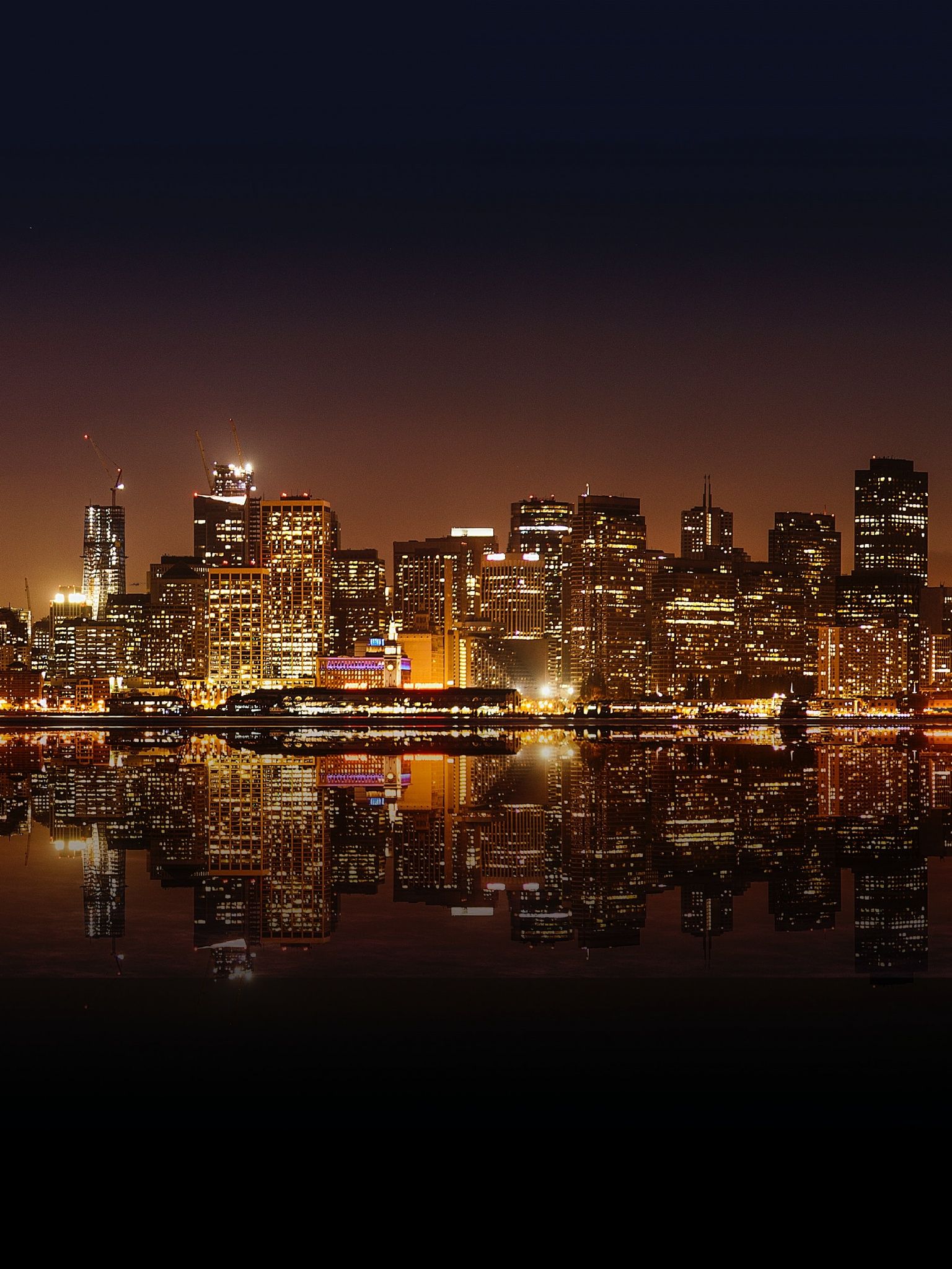 A city skyline at night with water in the foreground - City, skyline