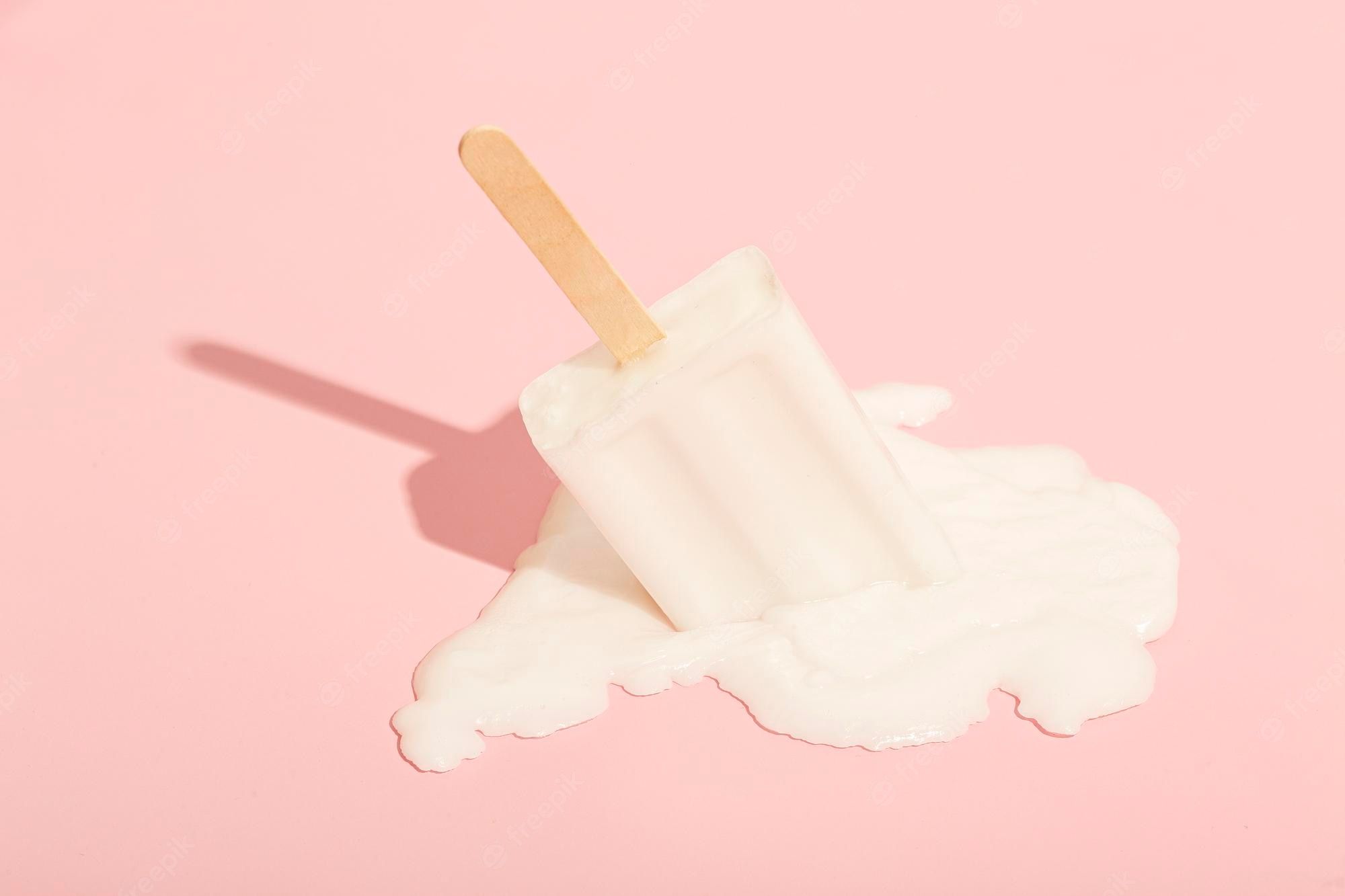 Premium Photo. White ice cream with a stick melts on a pastel pink background minimal summer concept