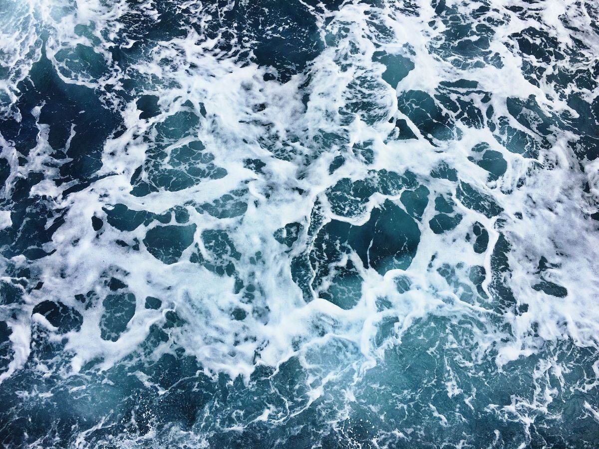 A photograph of the ocean with white froth on top. - Ocean