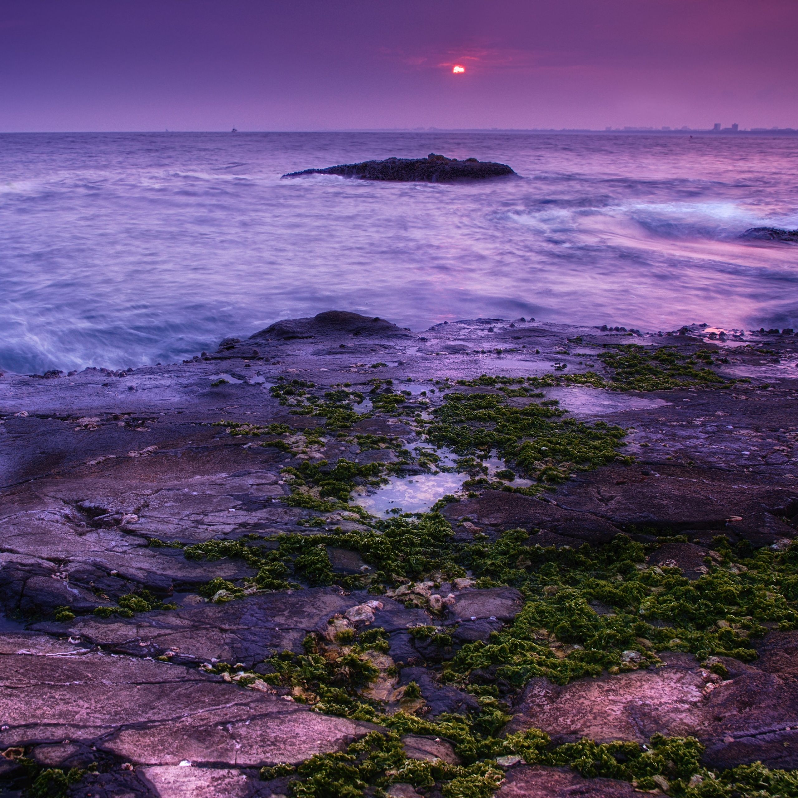 A sunset over the sea with a rocky shore in the foreground - Ocean
