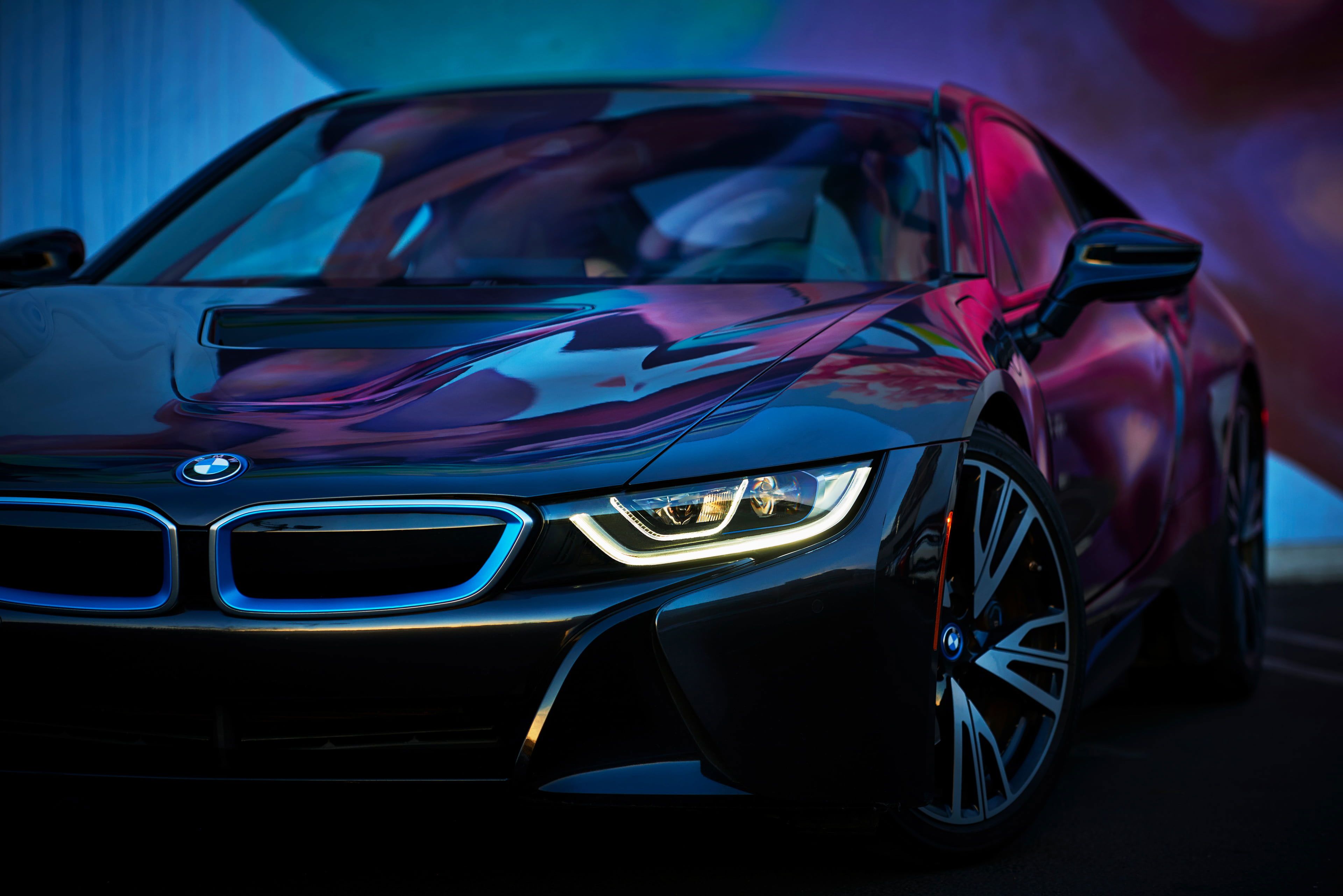The front of a black BMW i8 with its lights on - BMW