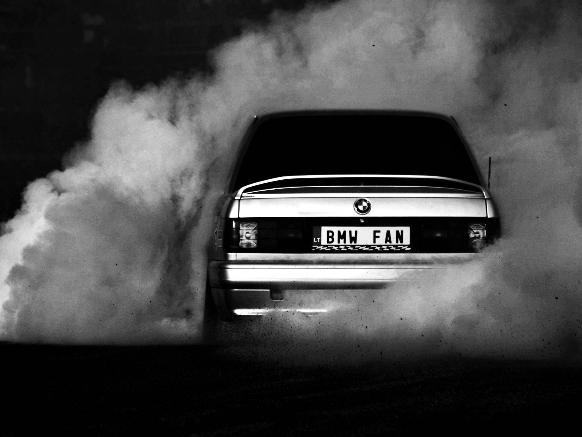 A black and white photo of smoke coming from the back end - BMW