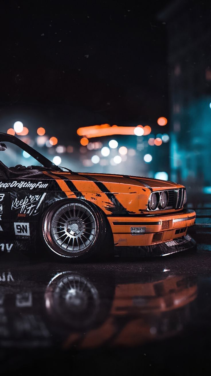 A black and orange BMW car on a wet road at night - BMW