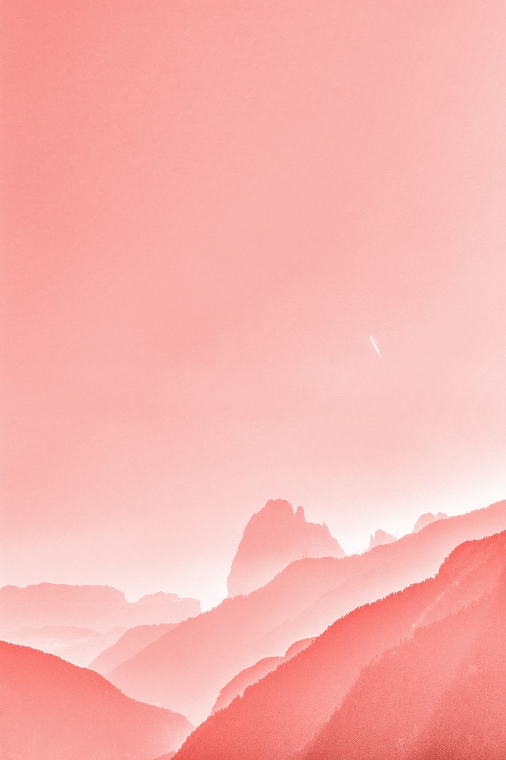 A plane flying over the mountains in pink - Salmon, coral