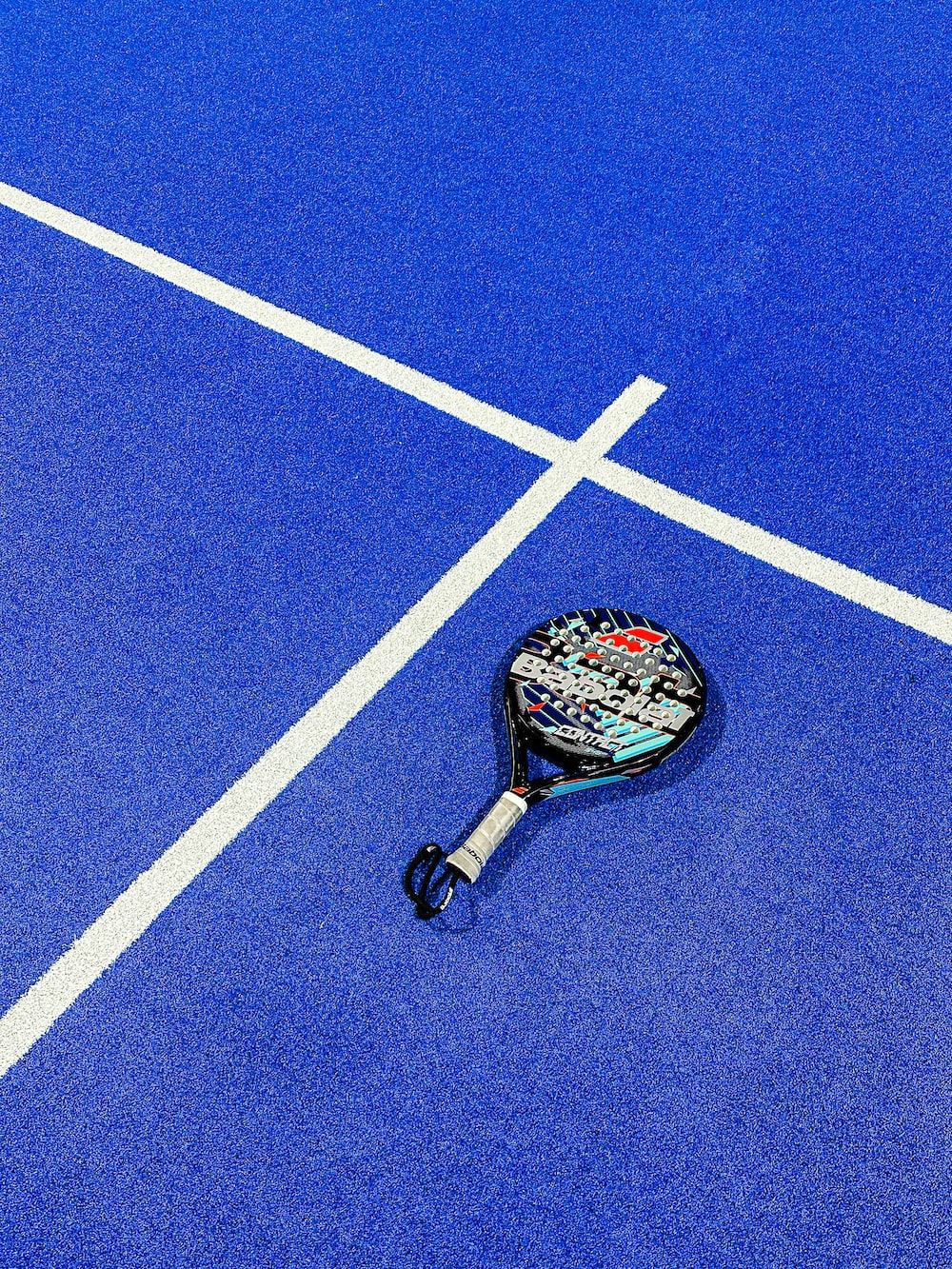 A tennis racket lying on a blue tennis court - Tennis