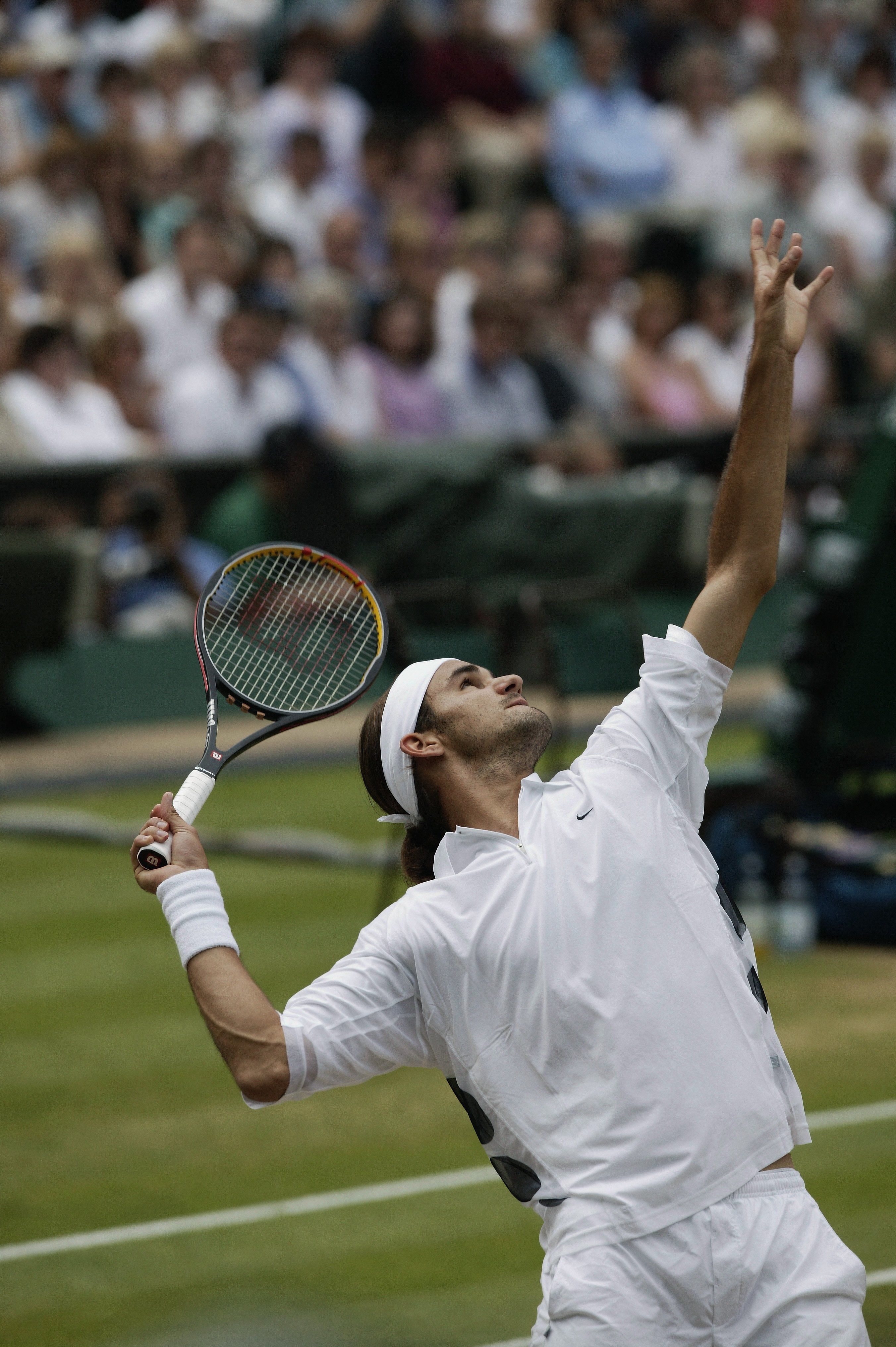 A tennis player serving the ball in front of a crowd of people. - Tennis