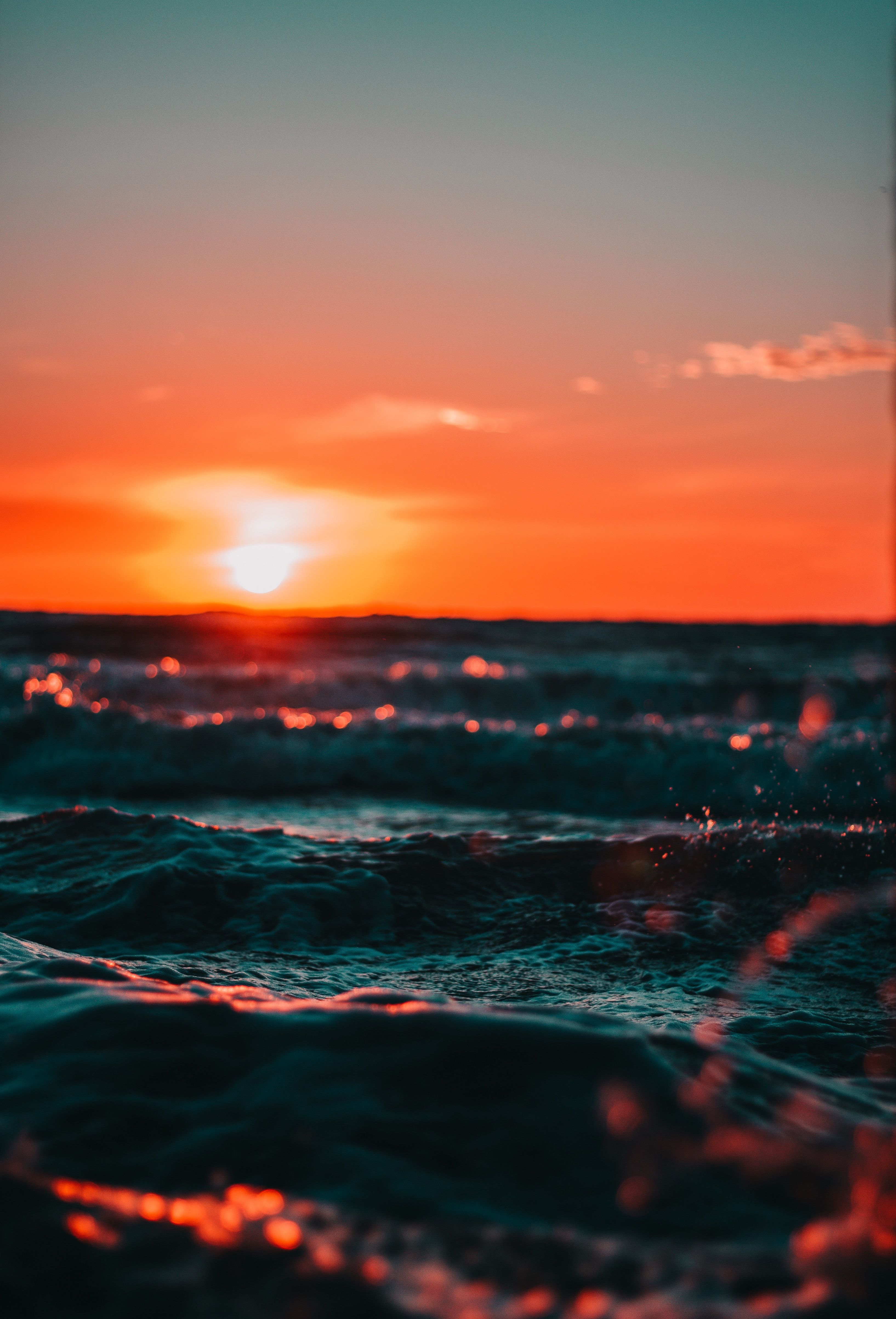 A sunset over the ocean with the sun setting behind the waves - Sunset, sun, ocean
