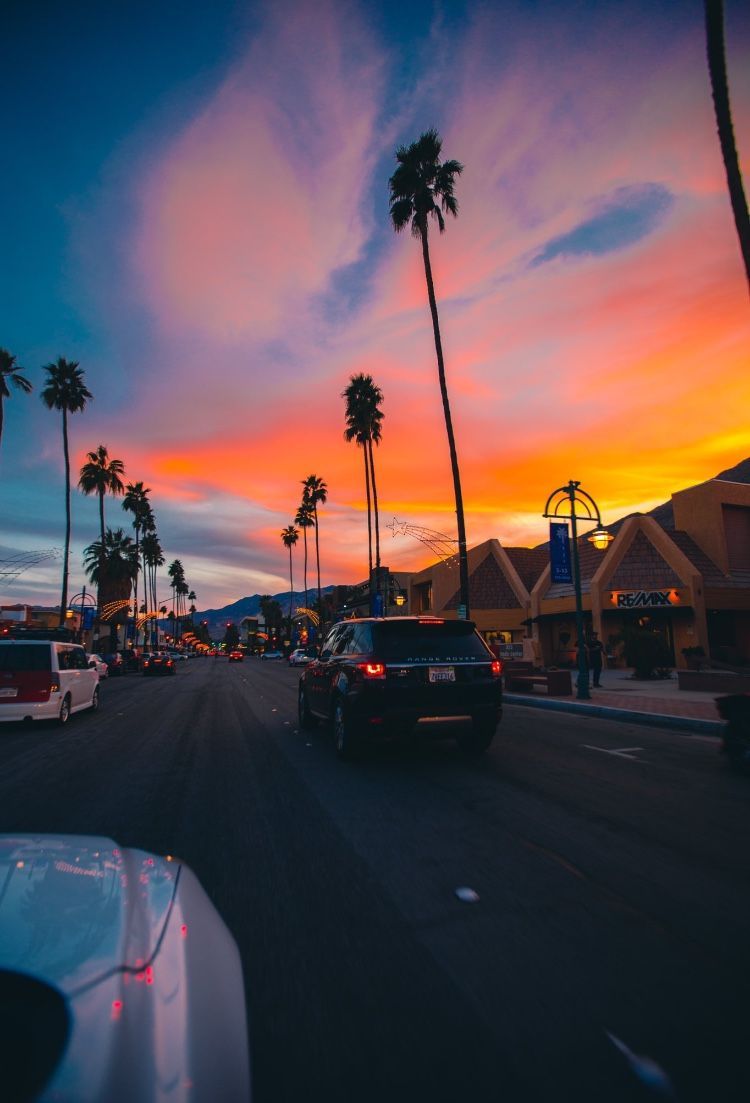 A sunset in palm springs with cars driving down the road - Sunset
