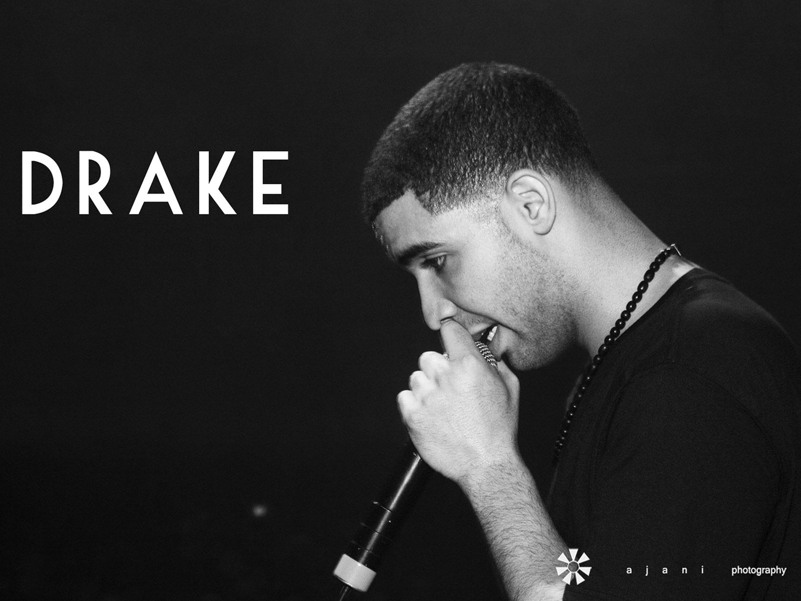 A man is holding his microphone and singing - Drake