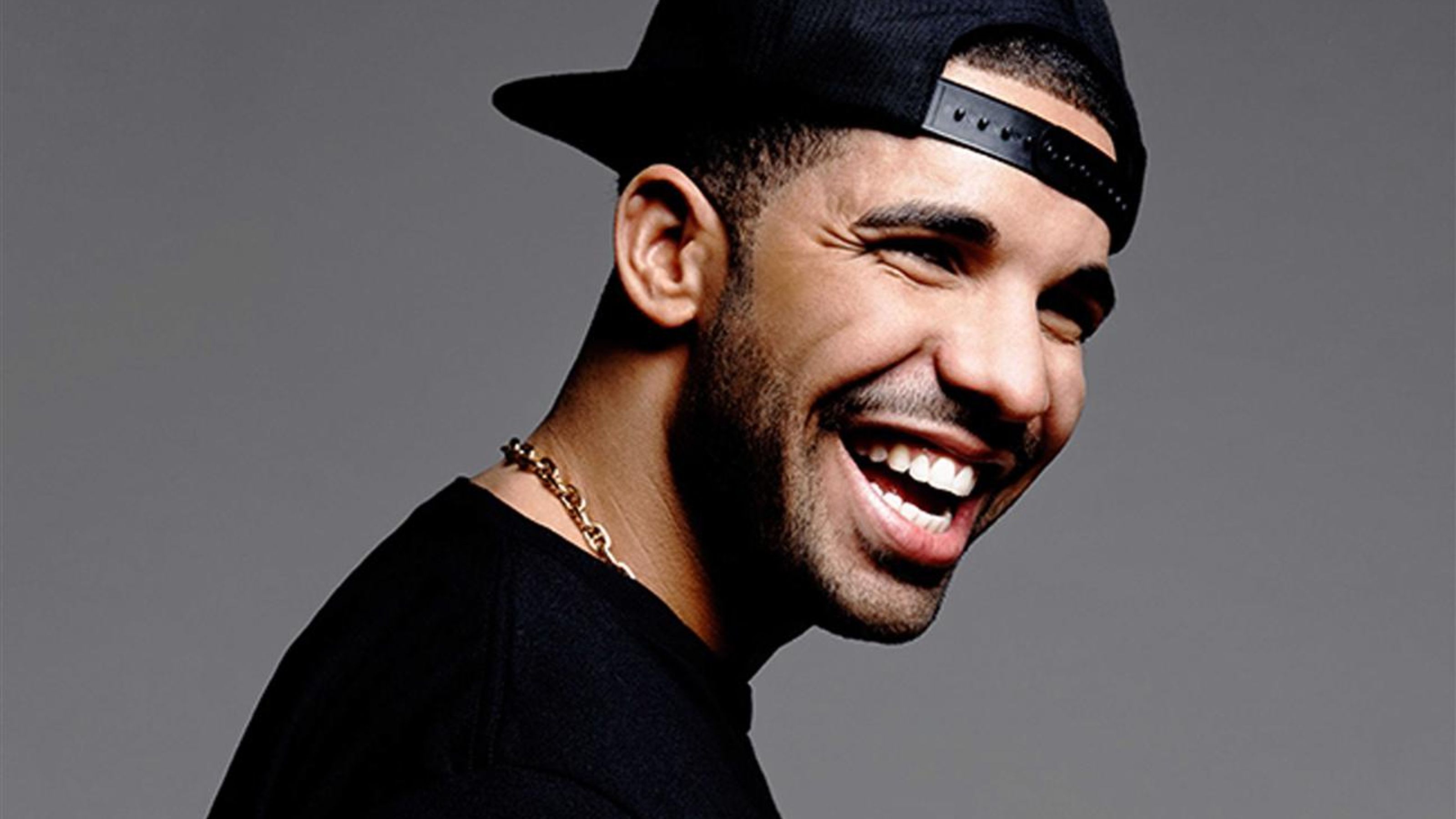 Drake smiling in a black hat and black shirt - Drake