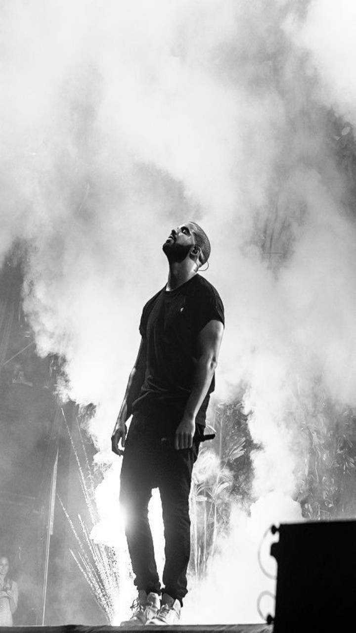 A man standing on stage with smoke in the background - Drake