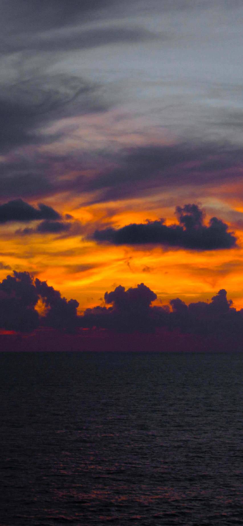 A photo of a sunset over the ocean with a dark purple and orange sky. - Sunset
