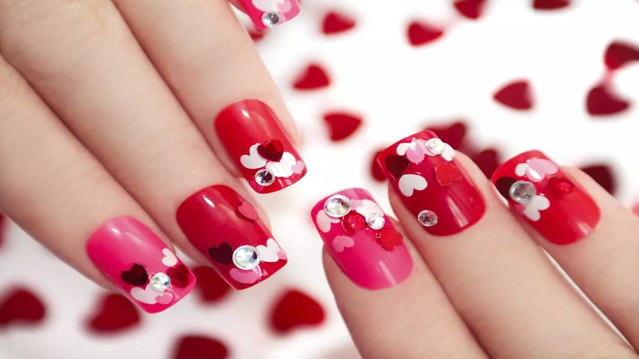 A woman with red and pink nails holding hearts. - Nails