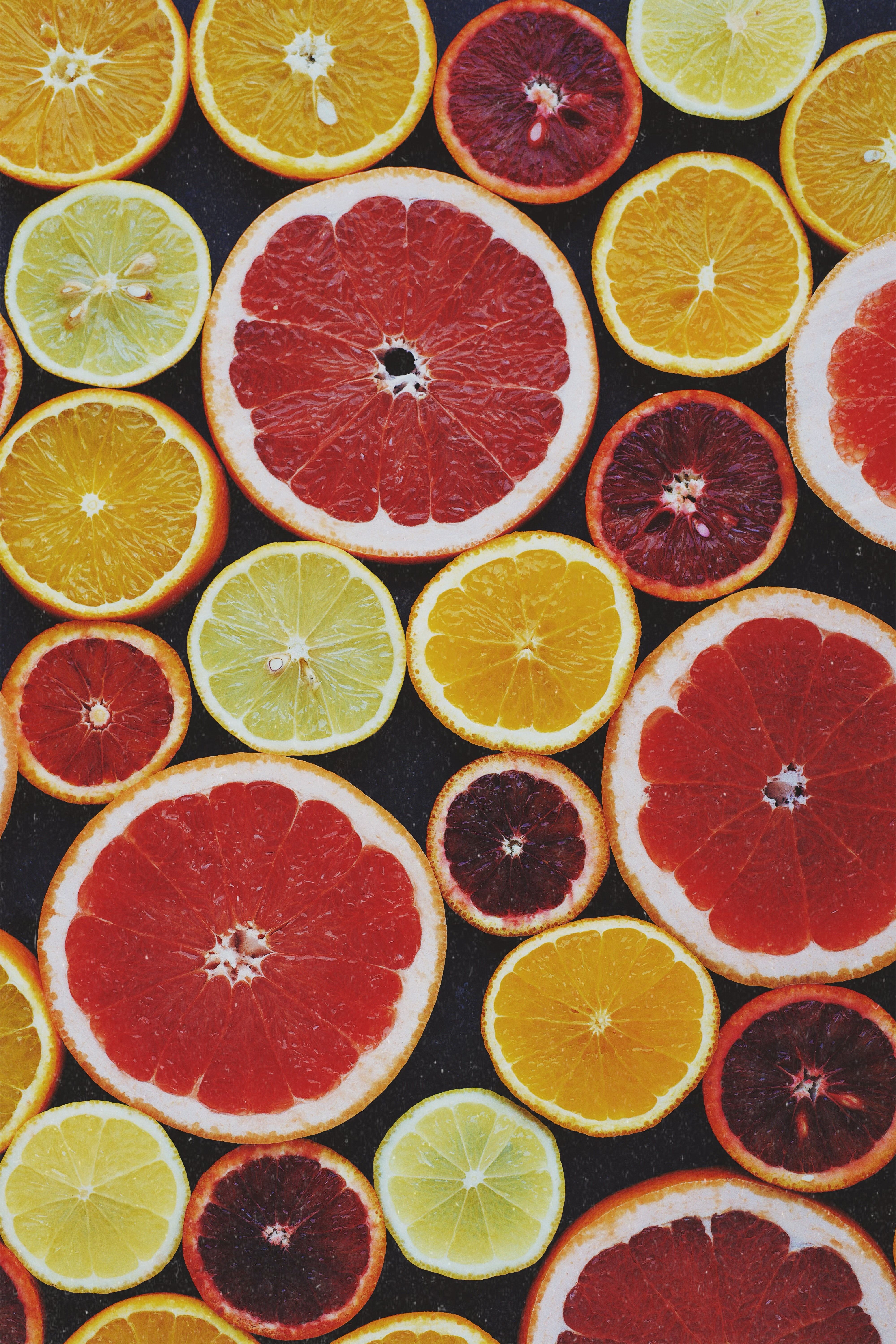 A variety of citrus fruit slices on a black background. - Fruit