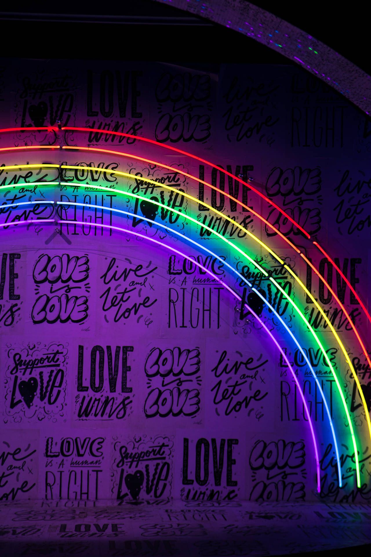 A rainbow of light on a wall with the word love written all over it - LGBT, pride, gay