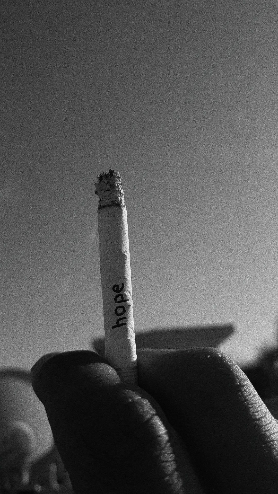 A person holding up an unlit cigarette - Smoke