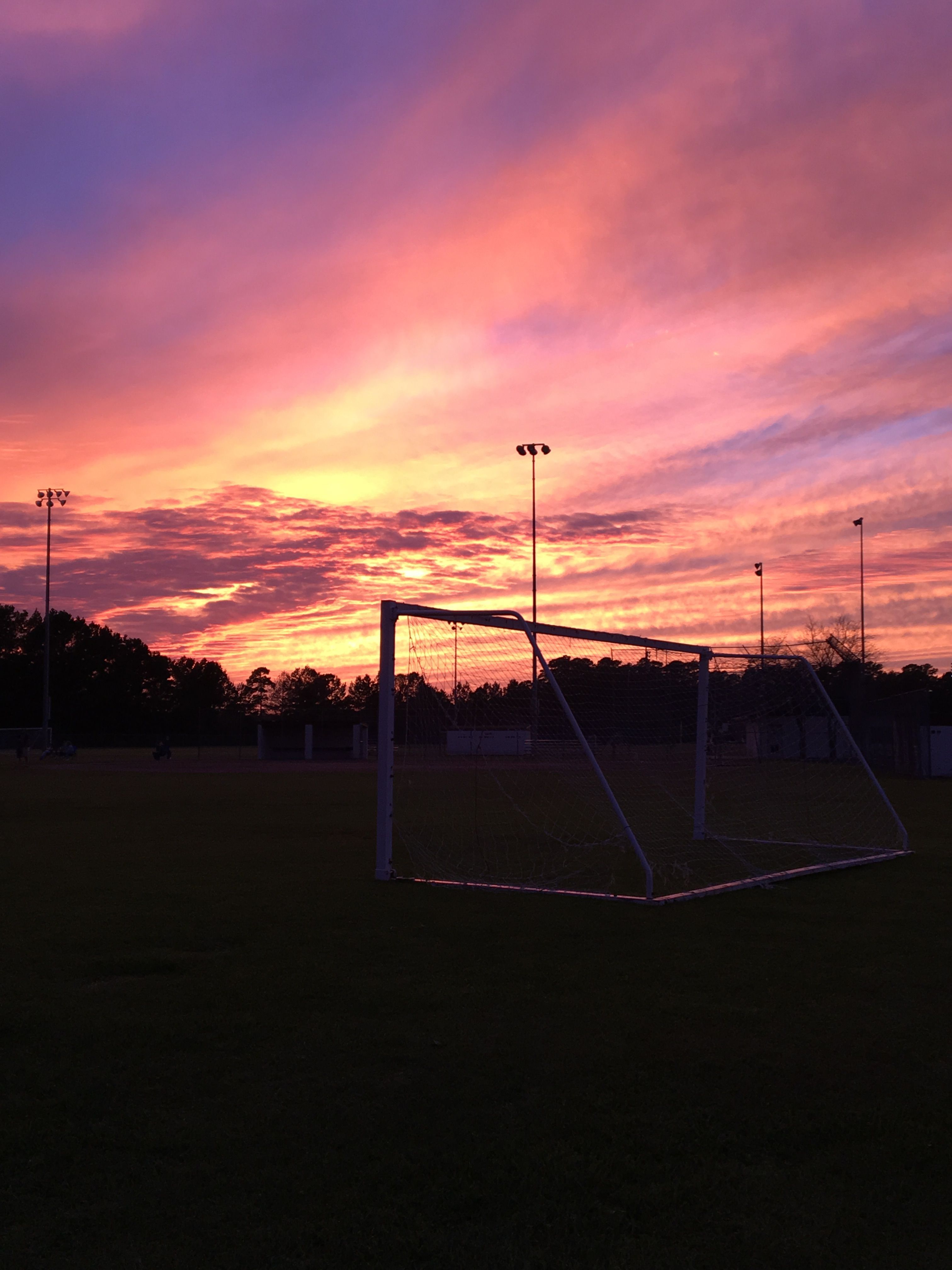 A soccer field with the sun setting in front of it - Soccer