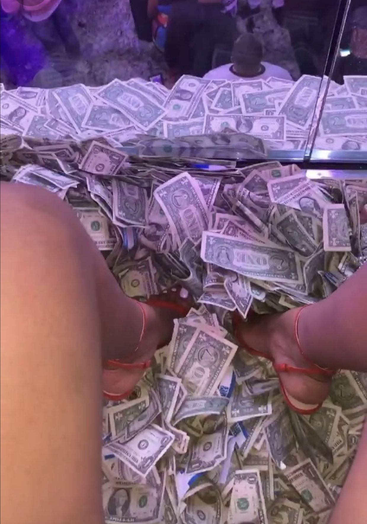 Woman stirs reactions as she sits on a bed of dollars in a club (Photos) - Money