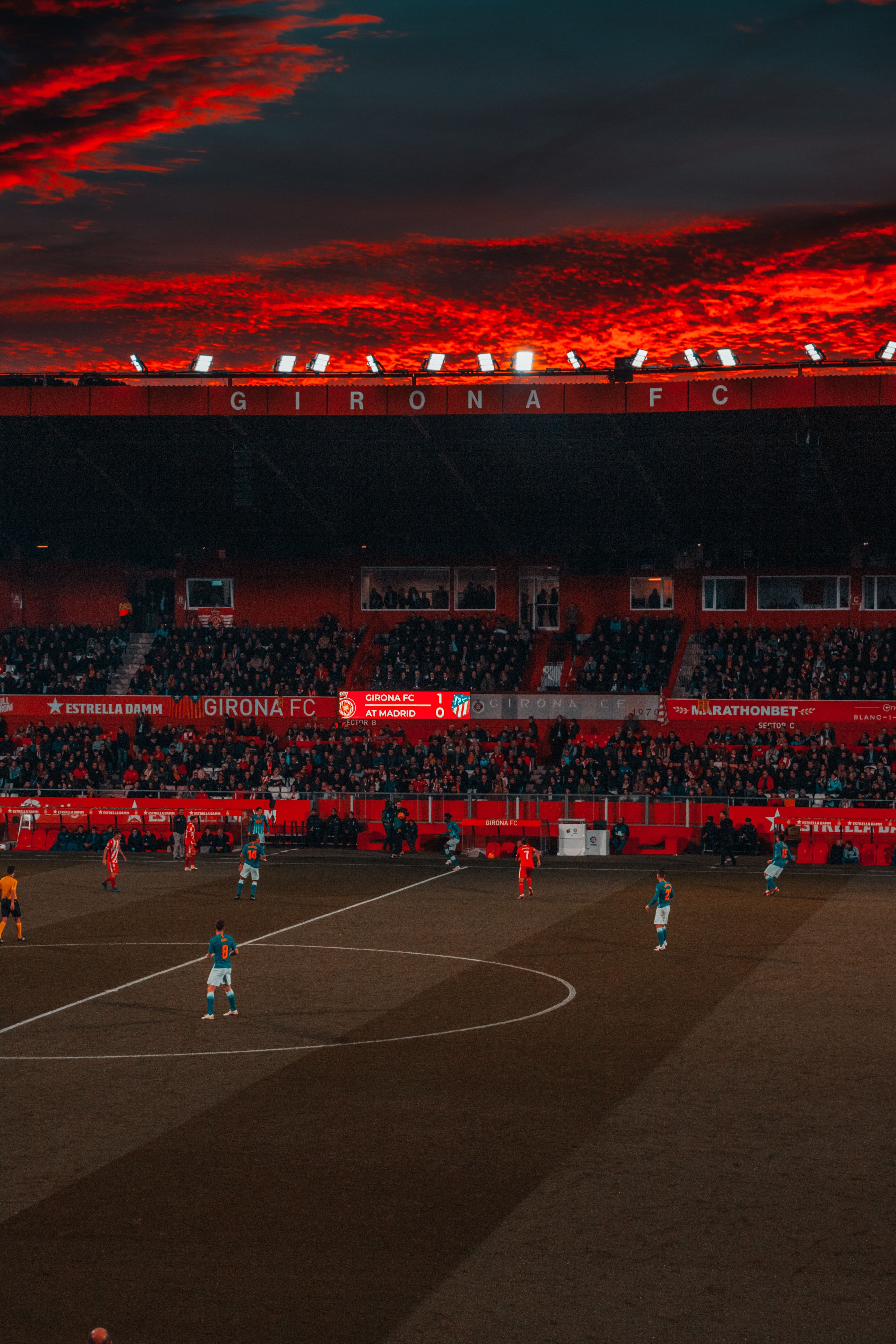 A soccer match with a red sunset in the background. - Soccer