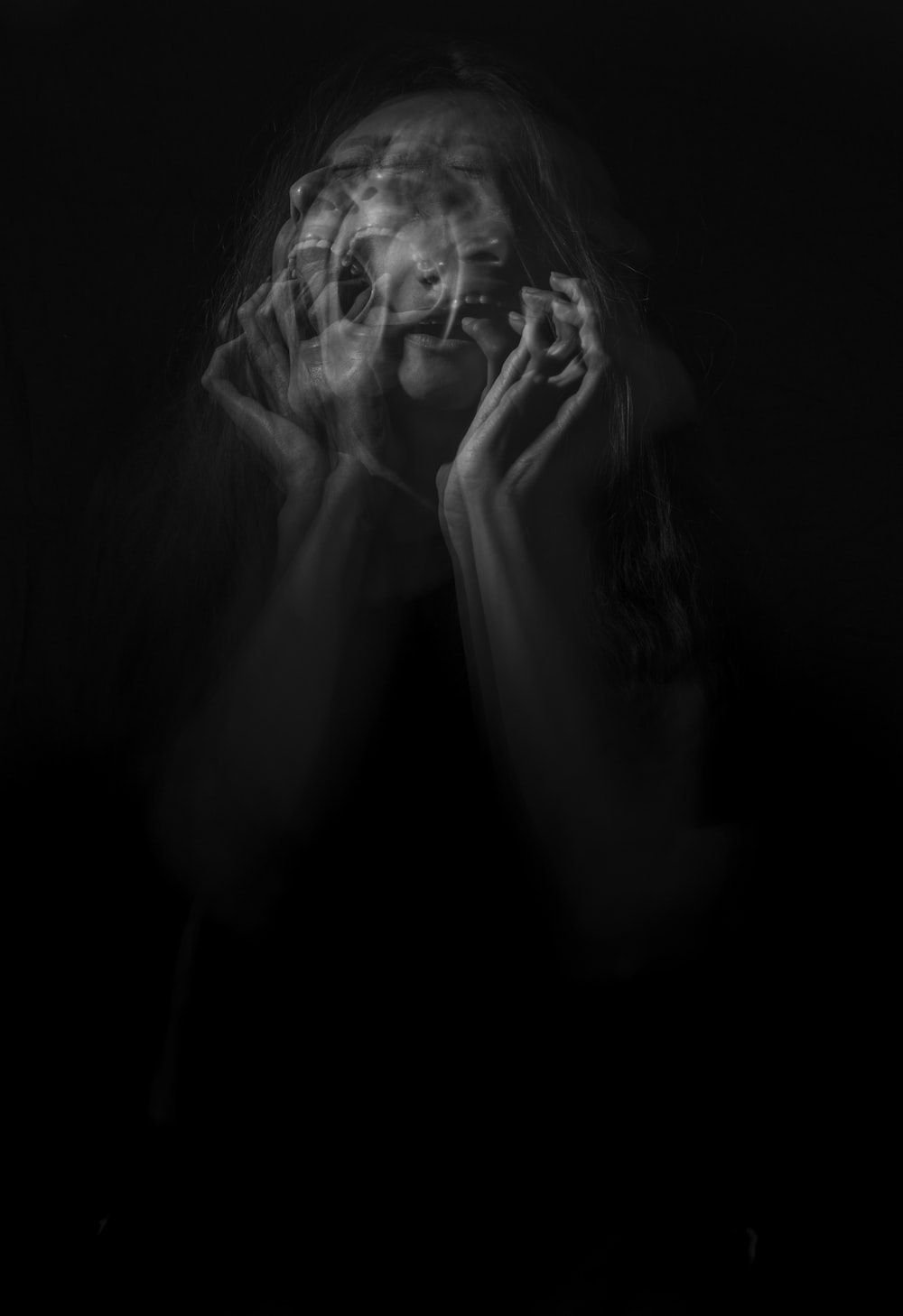 A woman with long hair covering her face with her hands. - Creepy
