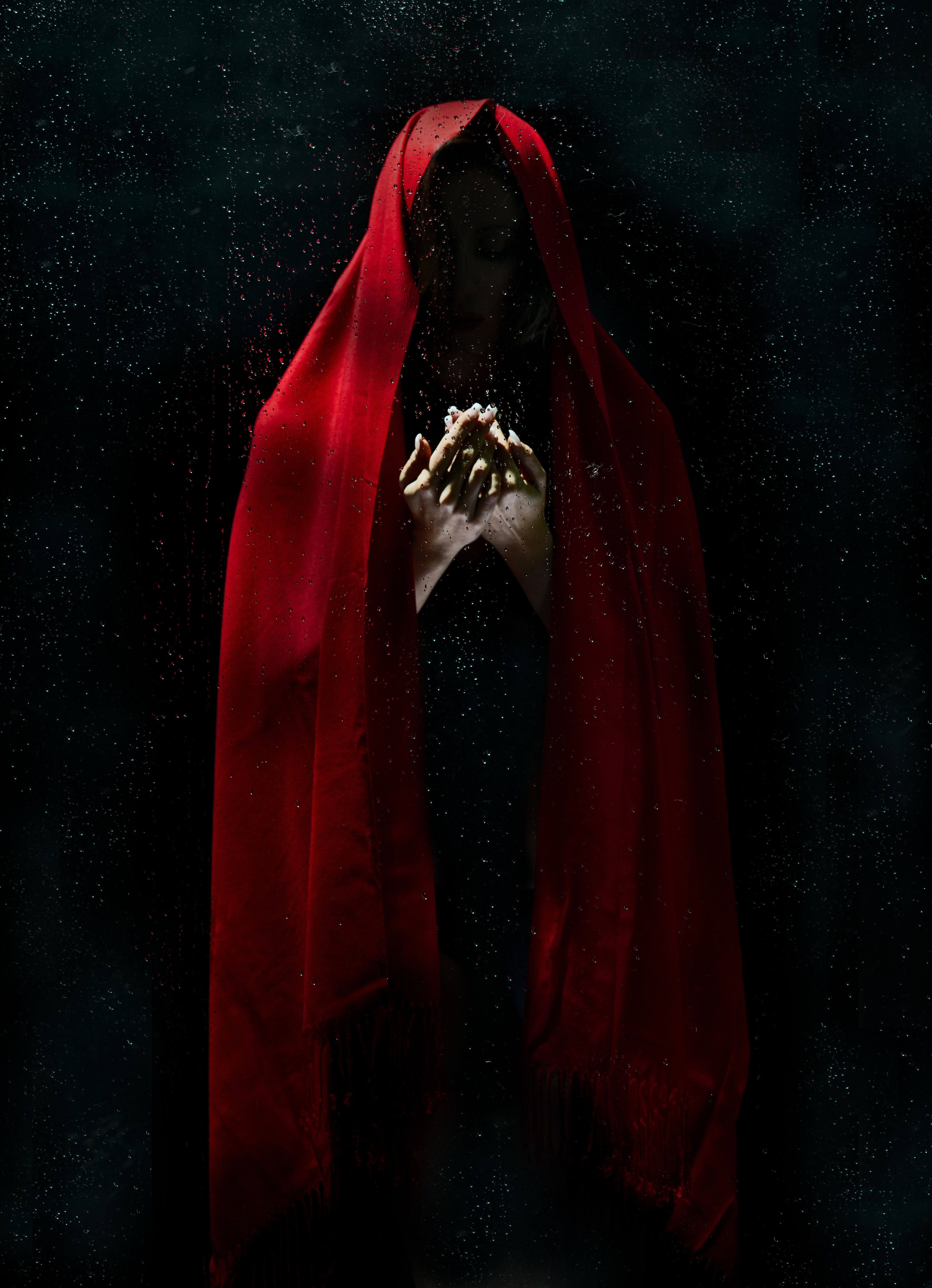 A woman in a red hooded cloak, her hands clasped in front of her. - Creepy, horror