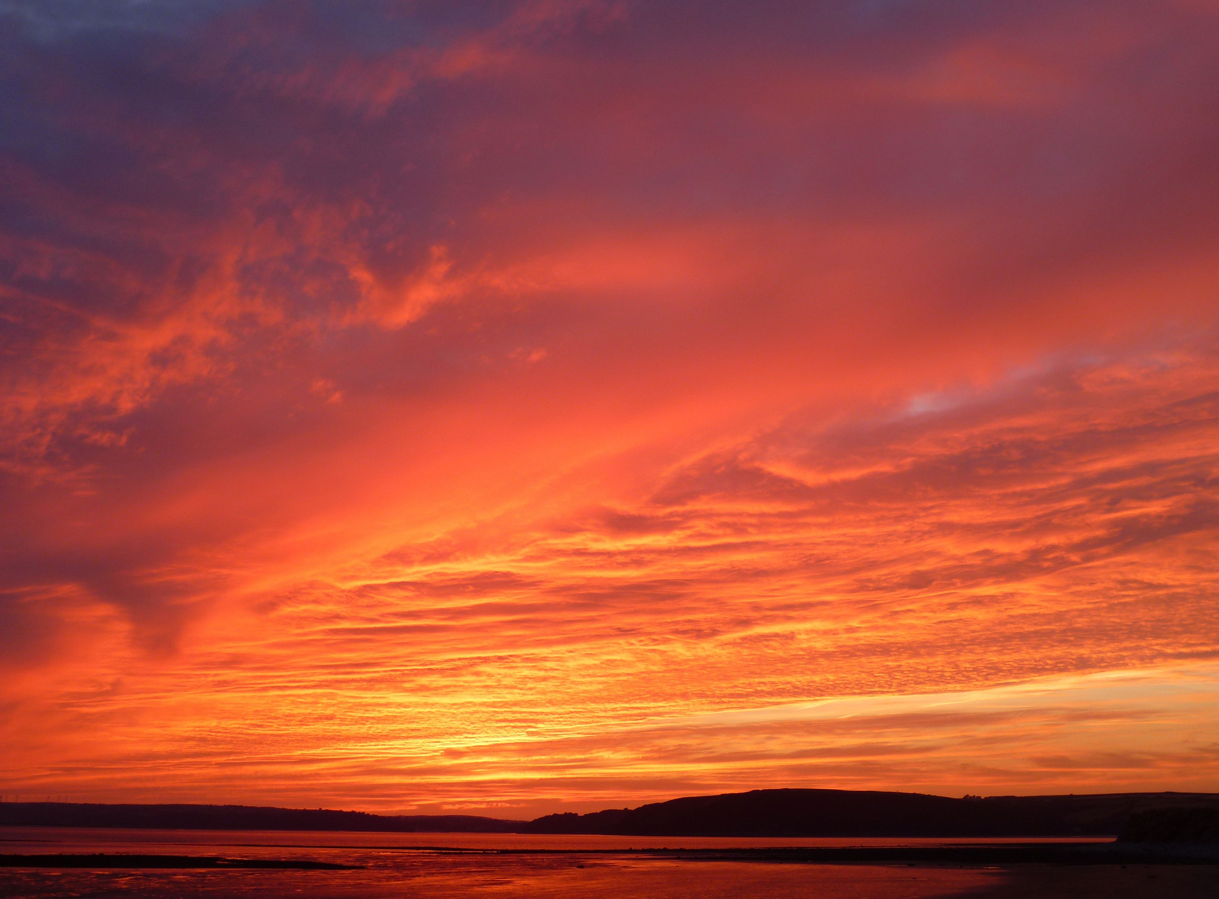A dramatic red and orange sunset over a body of water - Landscape