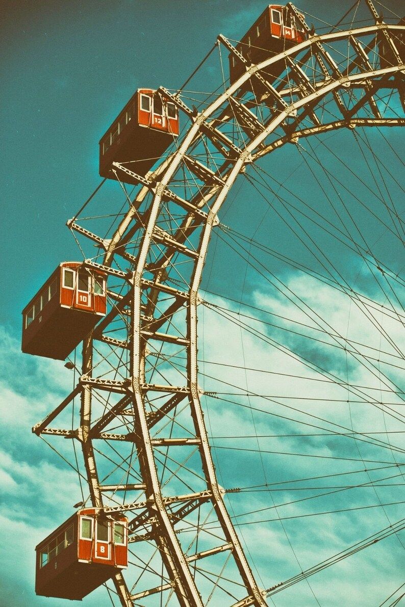 A ferris wheel with red cars against a blue sky. - 50s