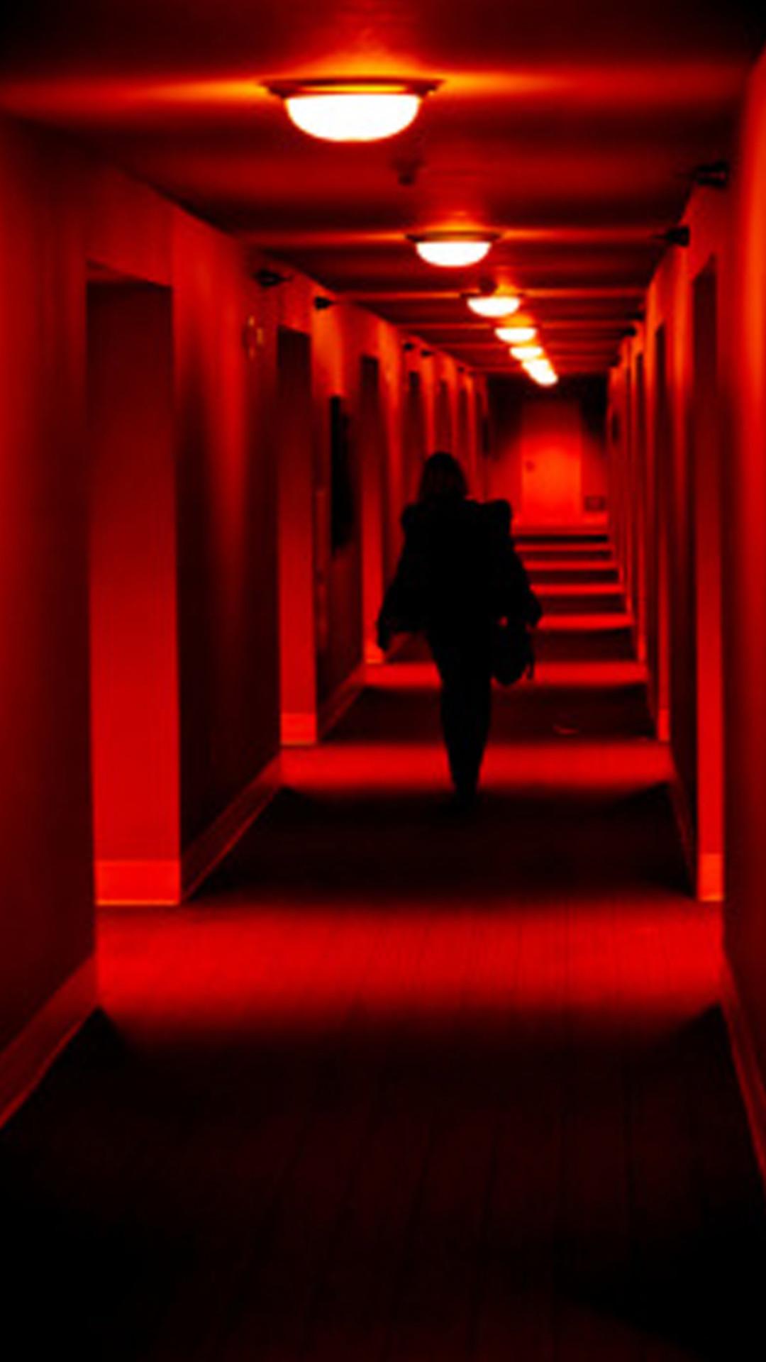 A person walking down an empty hallway - Red, light red, iPhone red