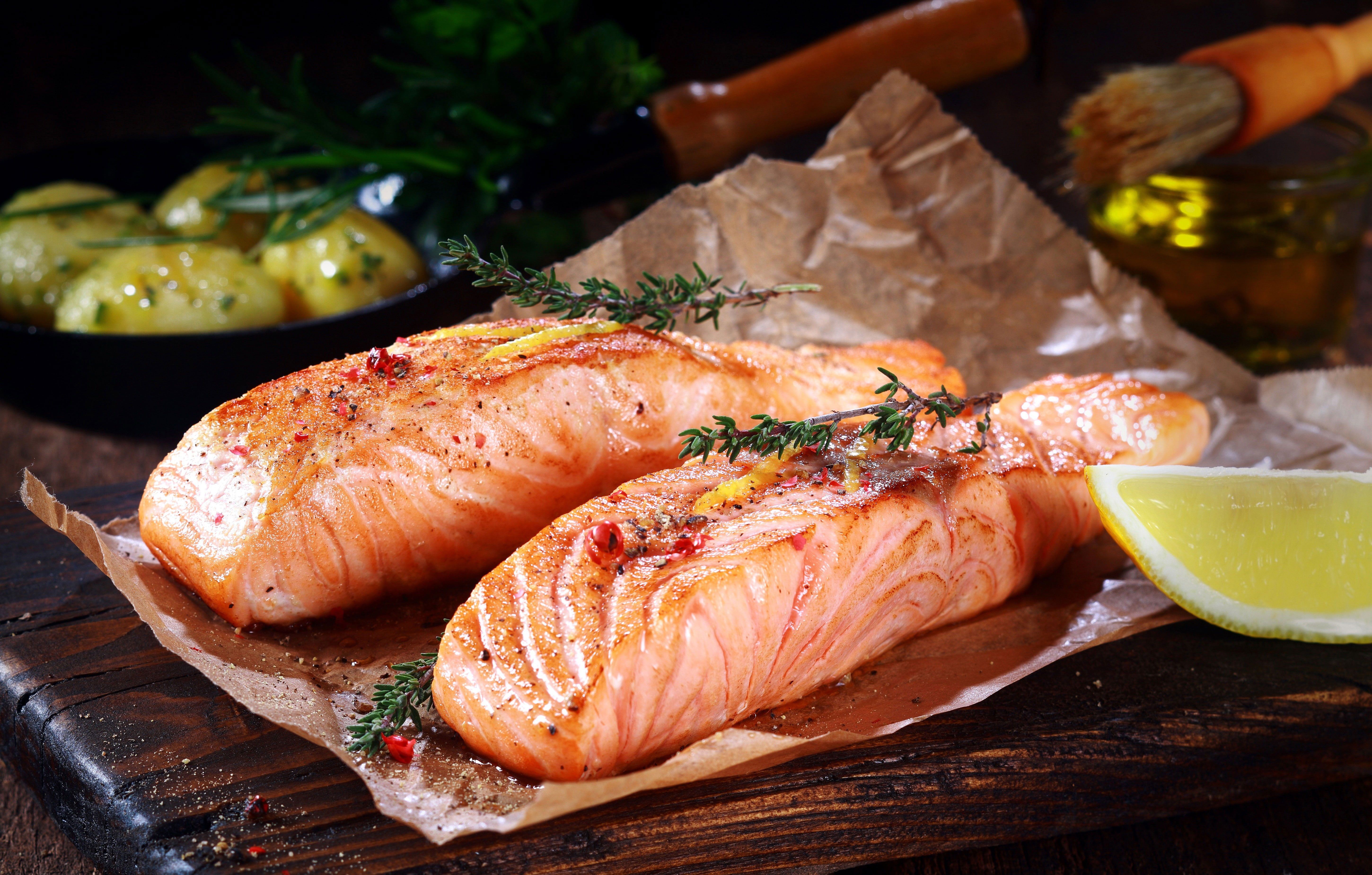 Two salmon fillets on a piece of parchment paper with lemon and herbs - Salmon
