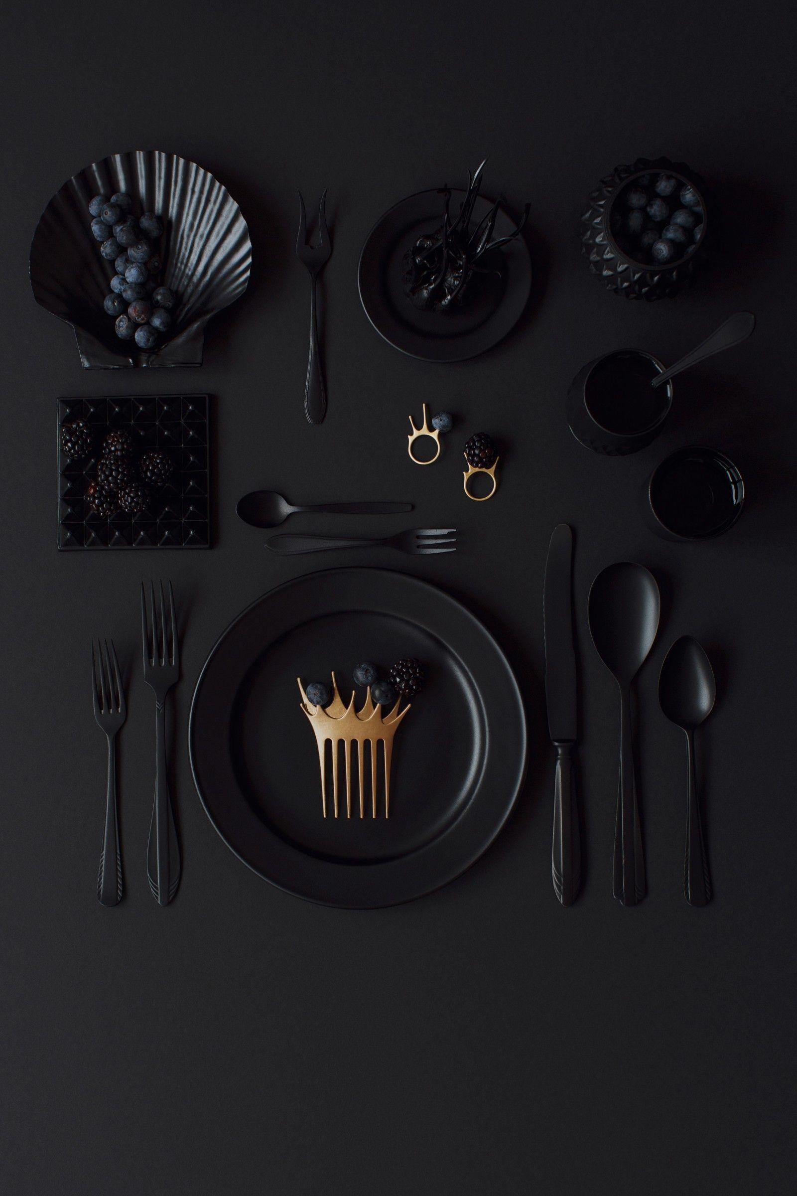 Black and gold flatware on a black table with black plates and black grapes. - Foodie, food