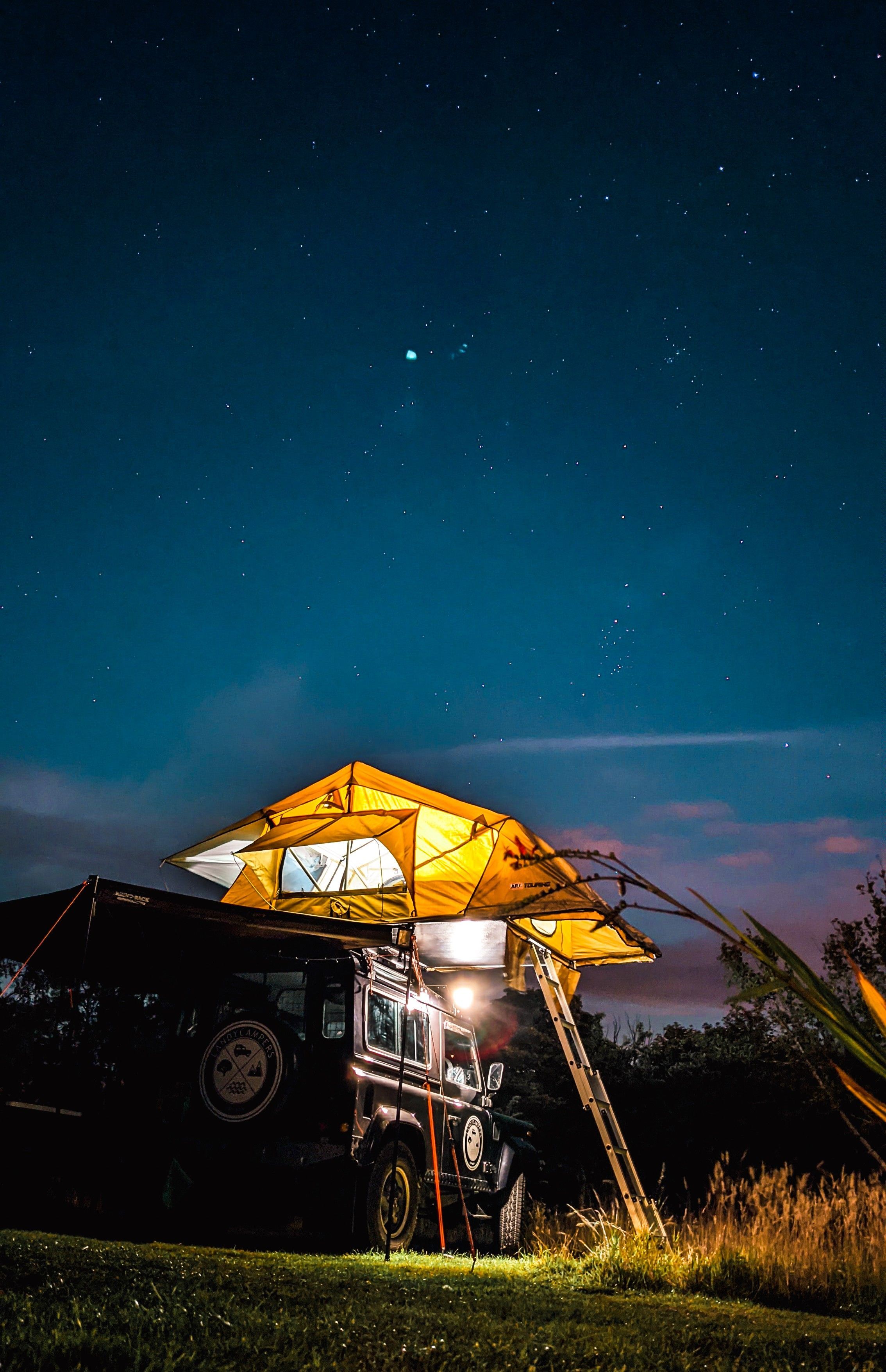 A truck parked underneath an awning with lights on - Camping