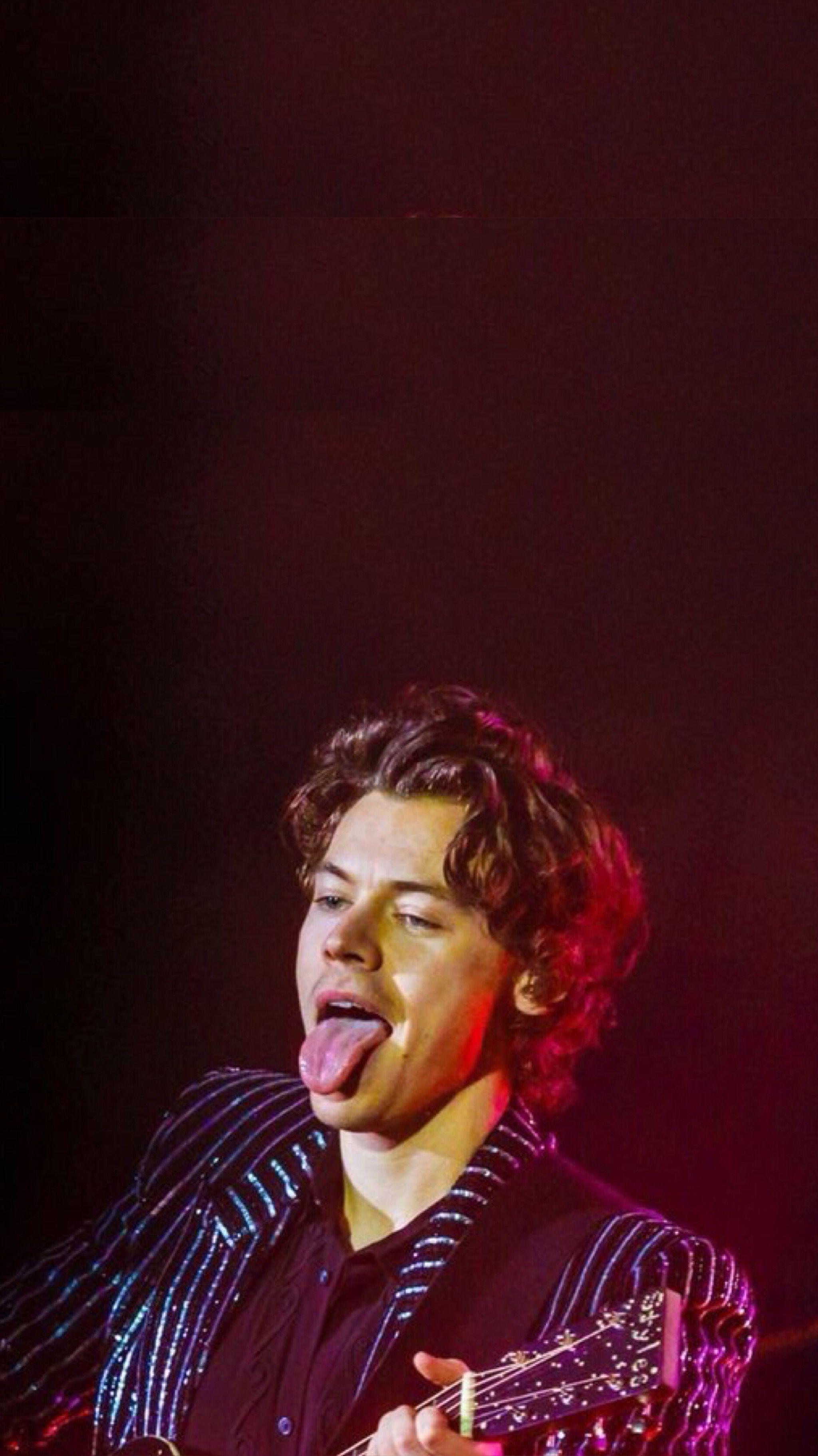 A man with his mouth open playing guitar - Harry Styles