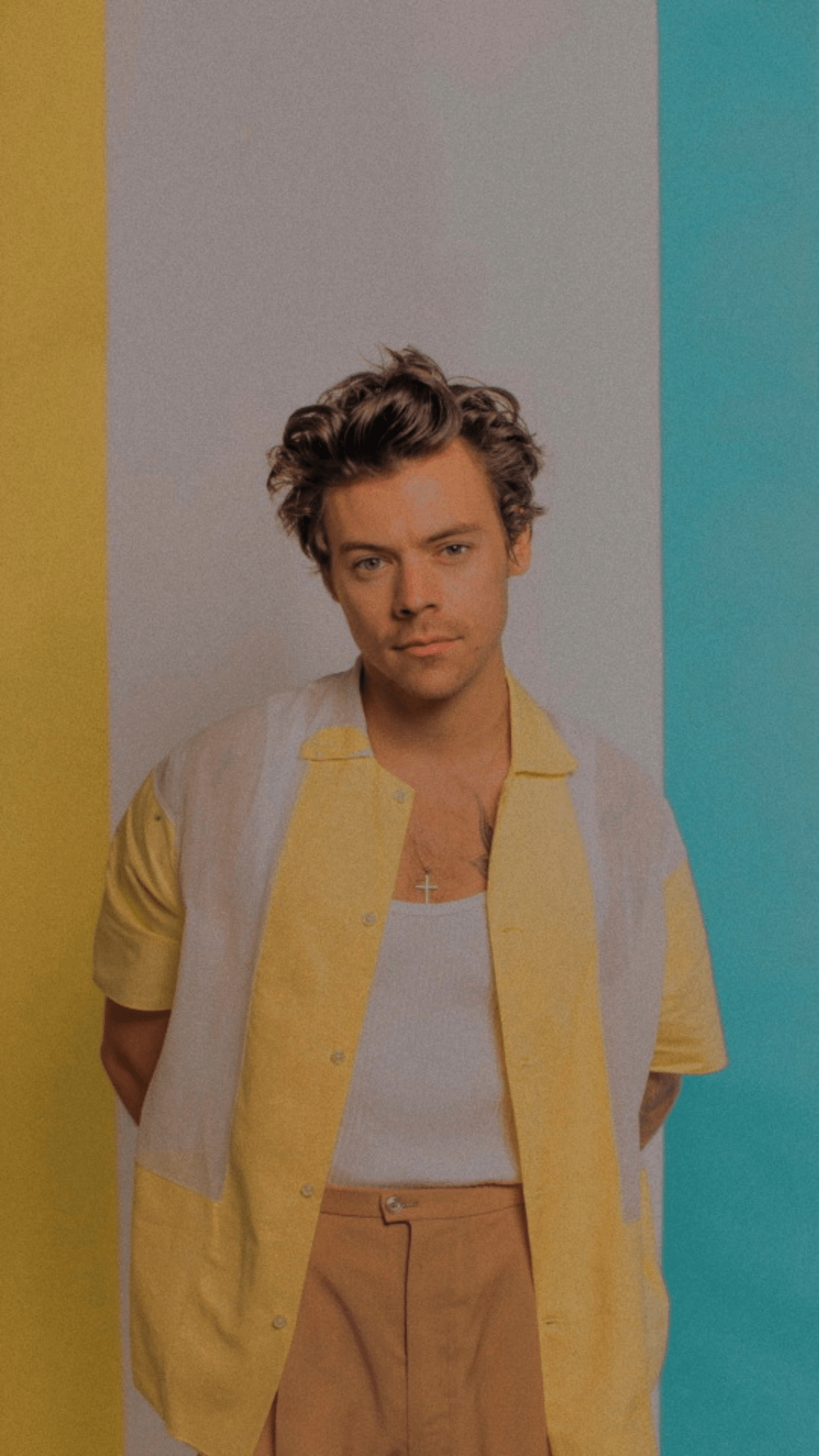 A man standing in front of an orange and yellow wall - Harry Styles