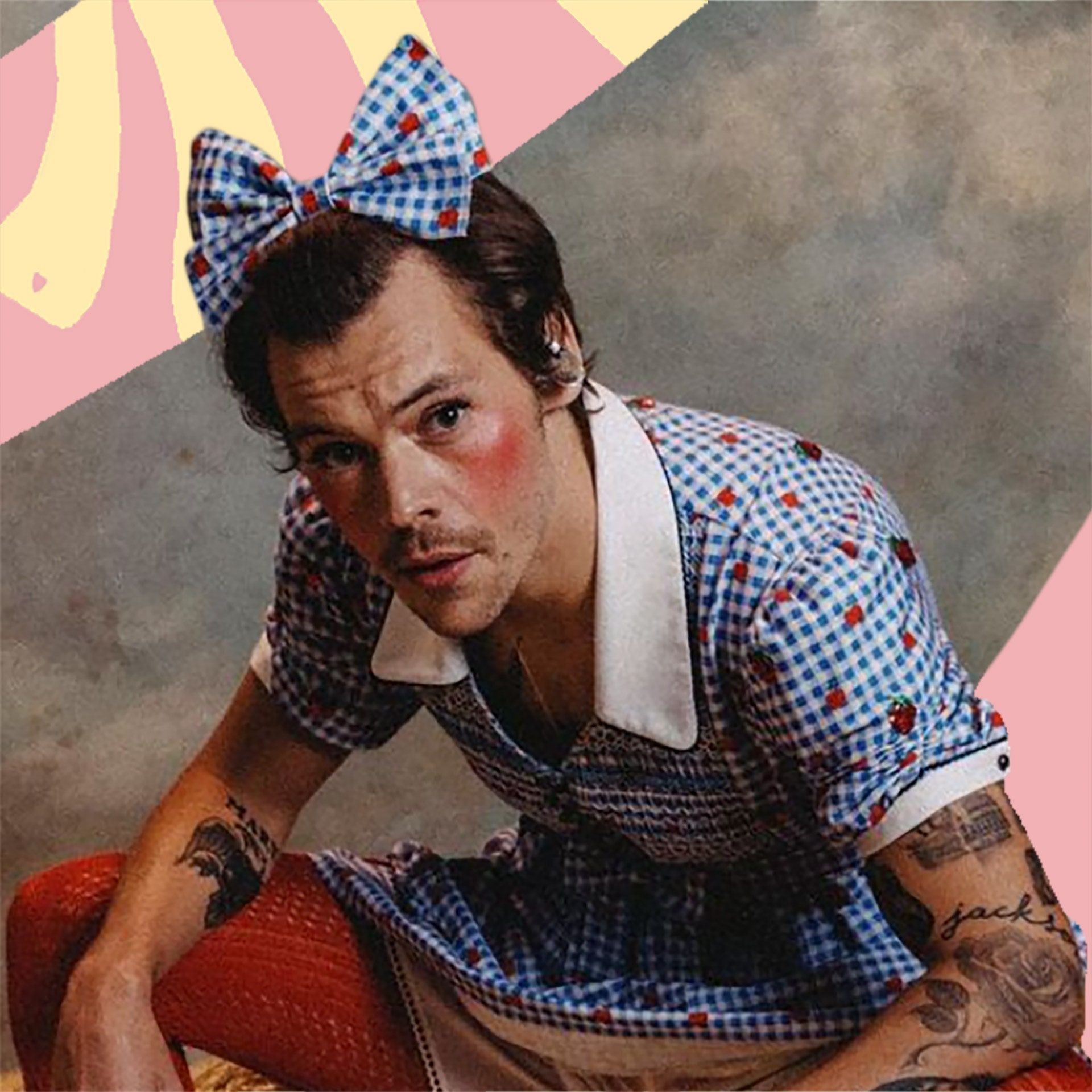 Harry Styles wears a blue gingham dress, red lip, and a blue bow in his hair in the 