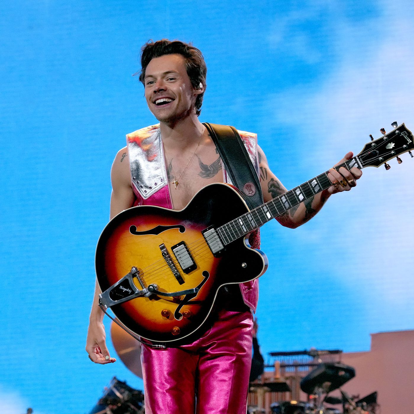 Harry Styles performs in a pink jumpsuit with a guitar - Harry Styles