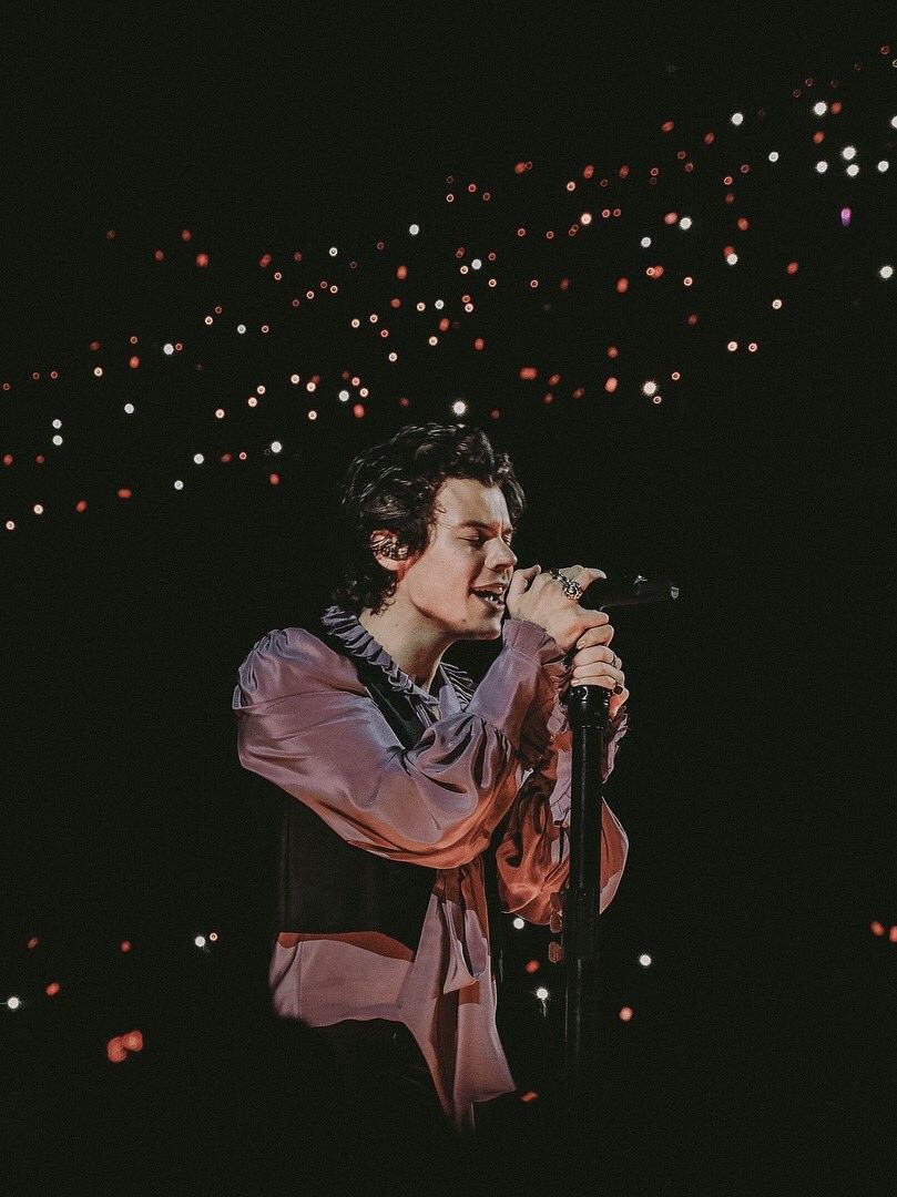 A man singing into microphone at concert - Harry Styles