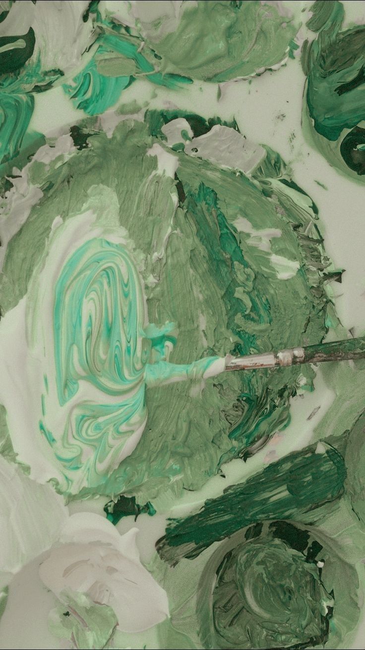 A close up of a paint palette with green and white swirled paint - Soft green, pastel green, light green