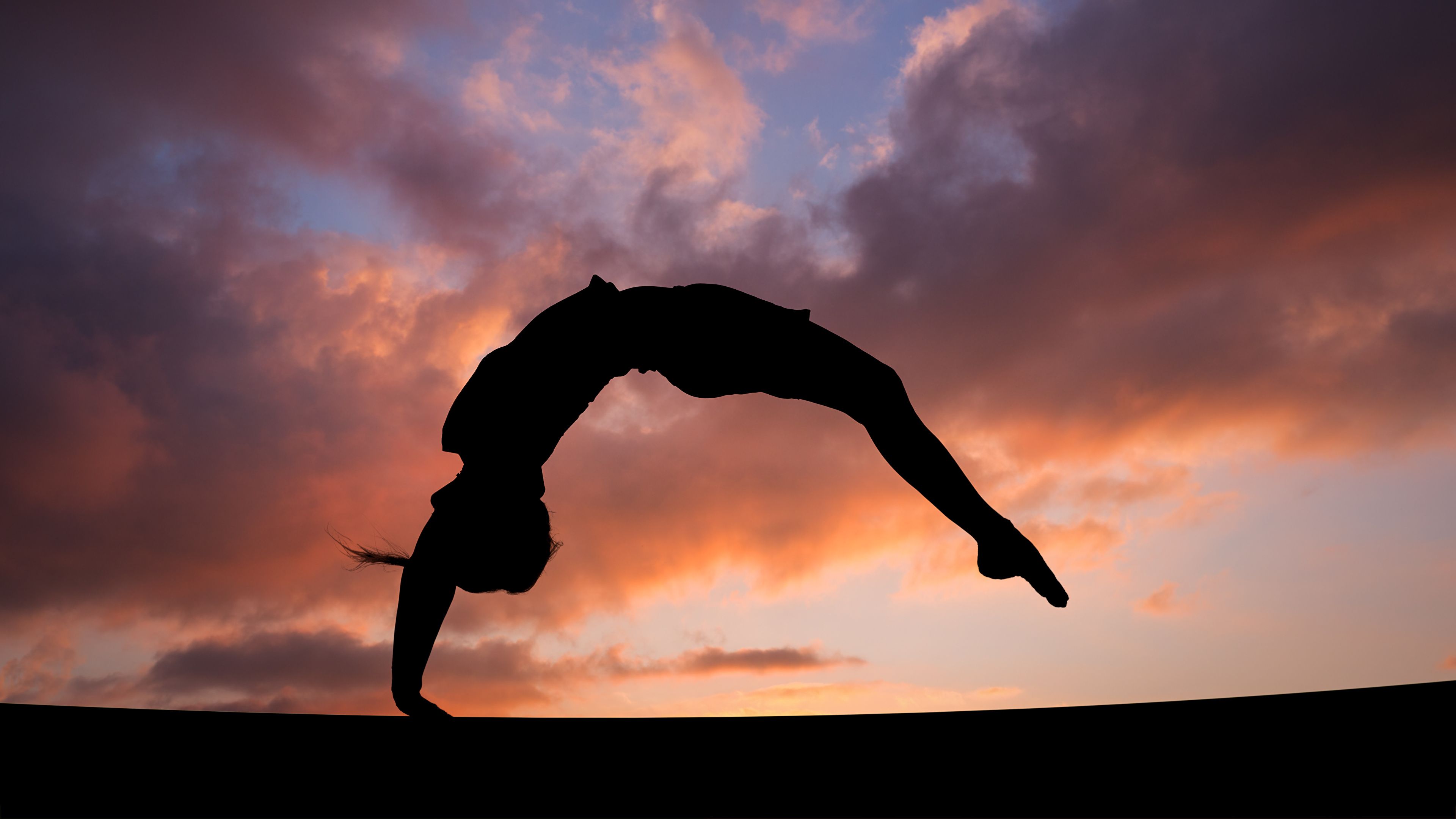 A silhouette of someone doing an acrobatic pose - Gymnastics