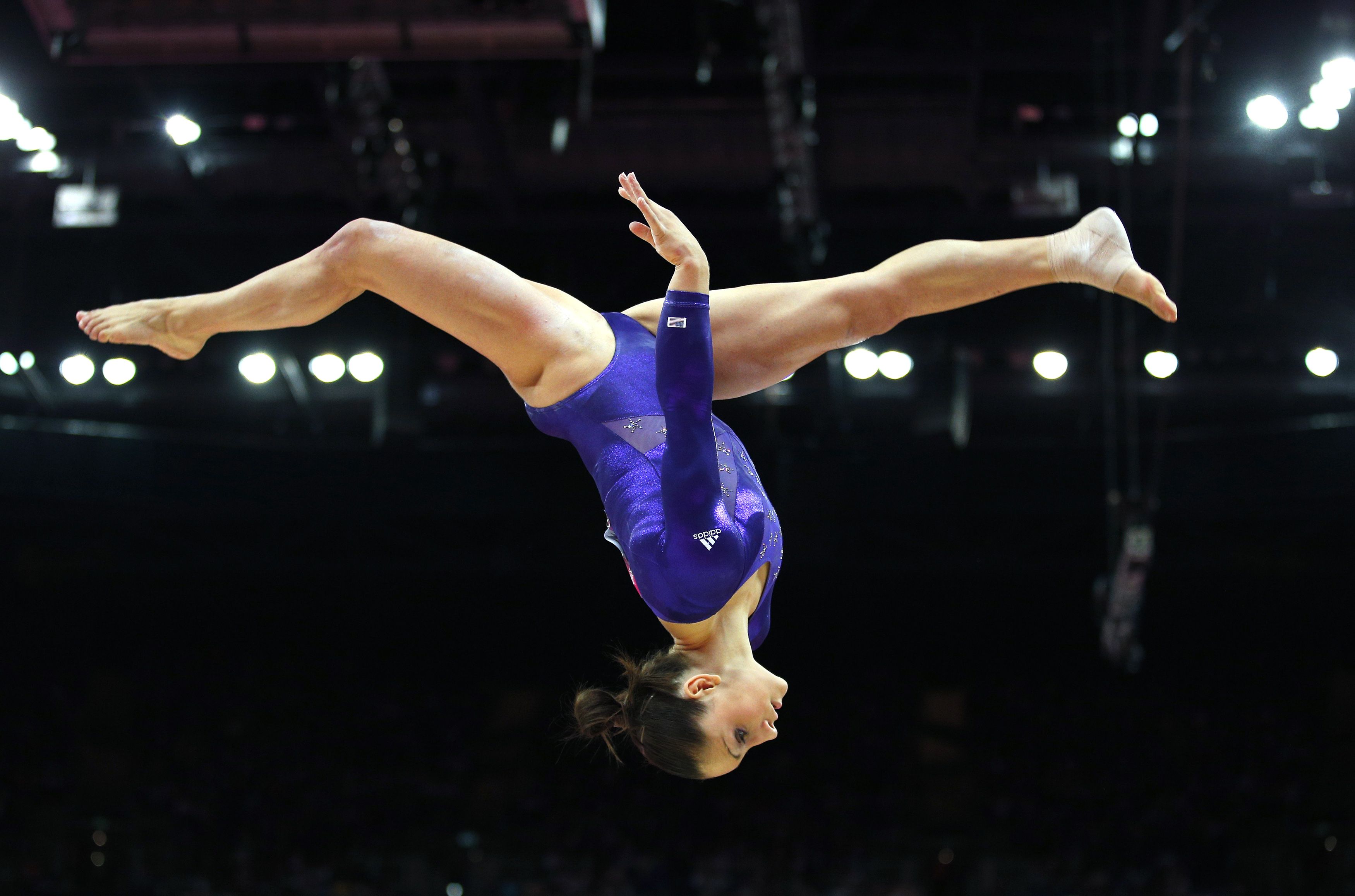 Gymnast with a ponytail in a purple leotard performing a flip - Gymnastics